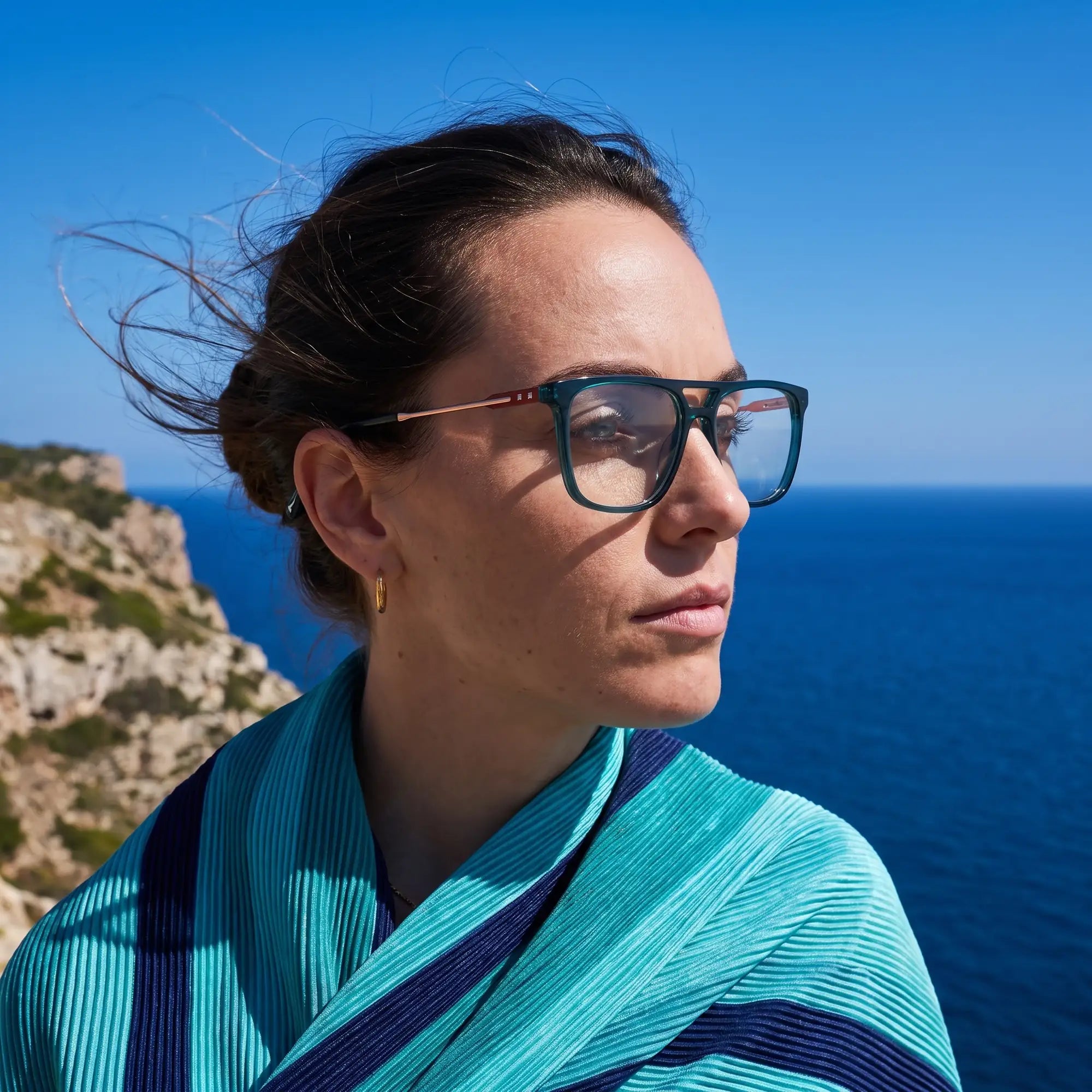 Fiore 10177 eyeglasses in green, worn by a model – campaign portrait, windswept portrait over the deep blue sea