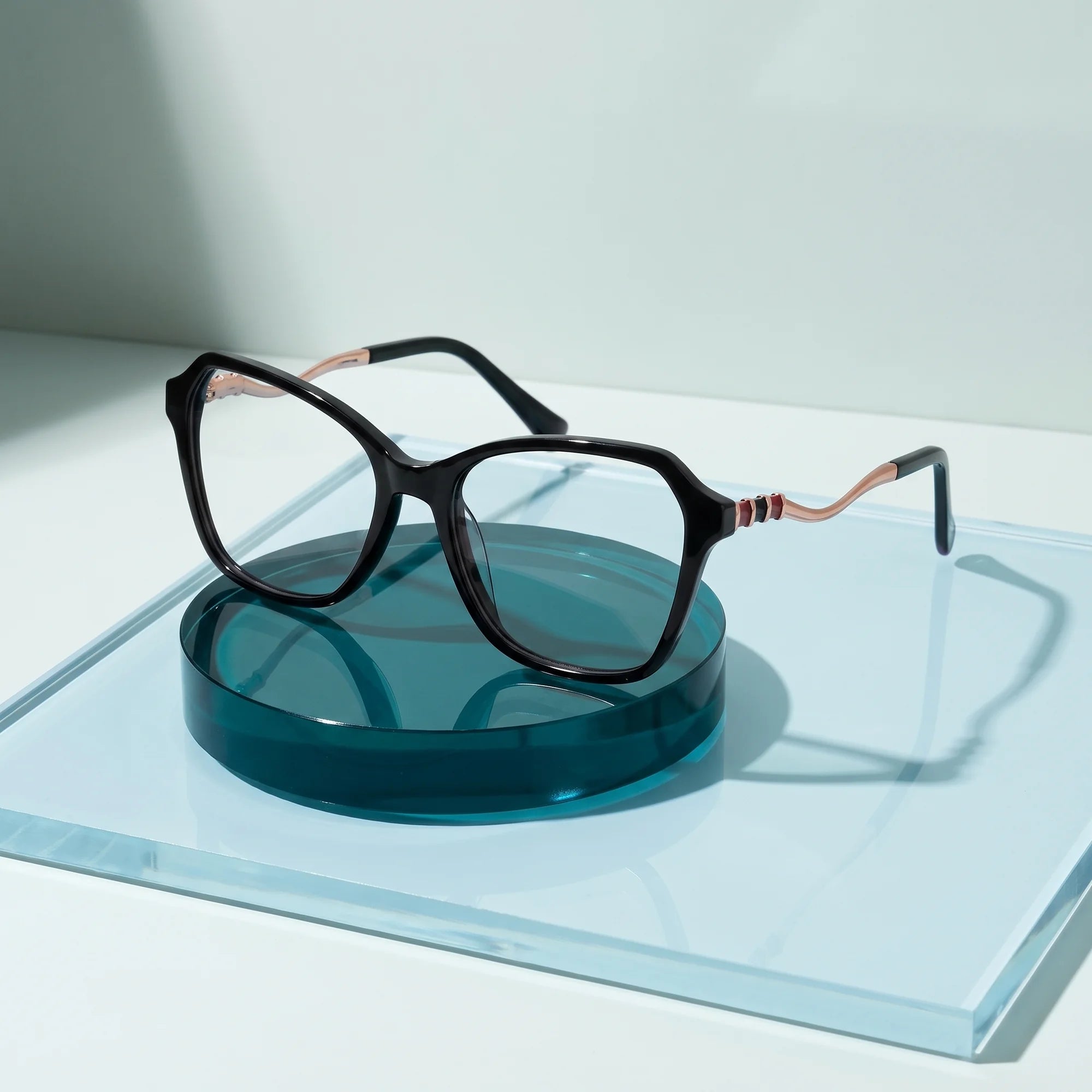Fiore 1030 eyeglasses in black – on a cobalt acrylic disc in soft daylight