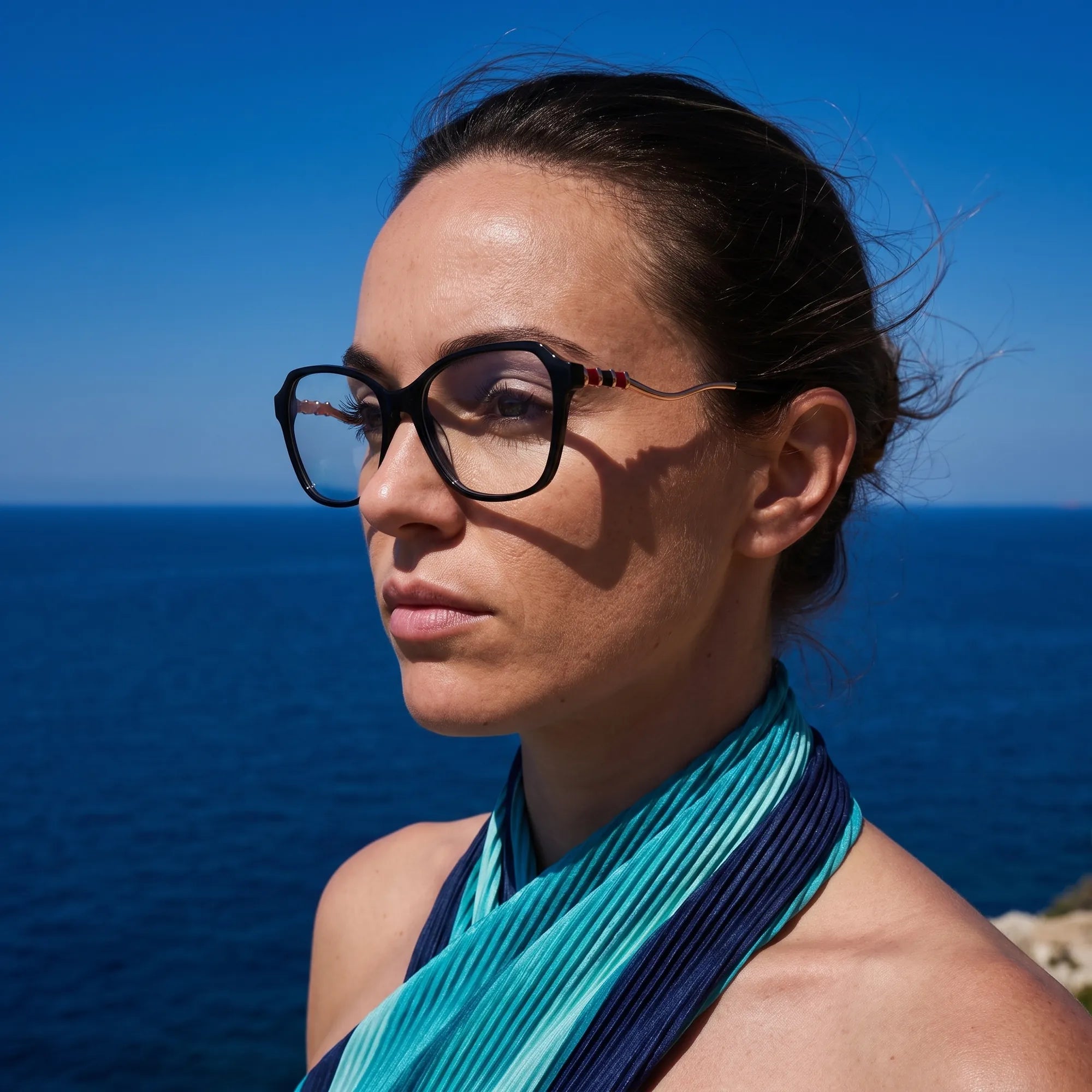 Fiore 1030 eyeglasses in black, worn by a model – campaign portrait, windswept portrait over the deep blue sea
