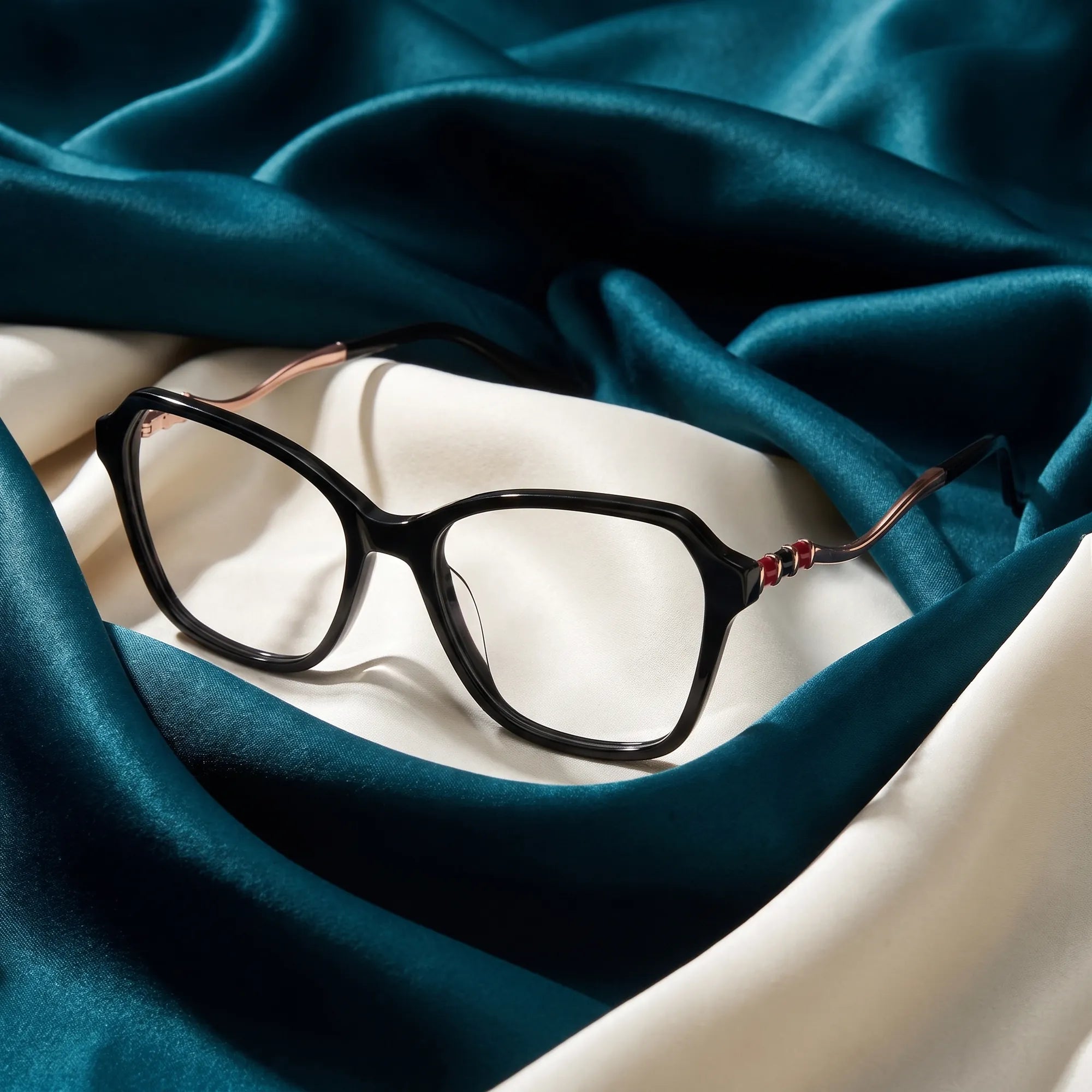 Fiore 1030 eyeglasses in black – resting on draped teal and ivory silk