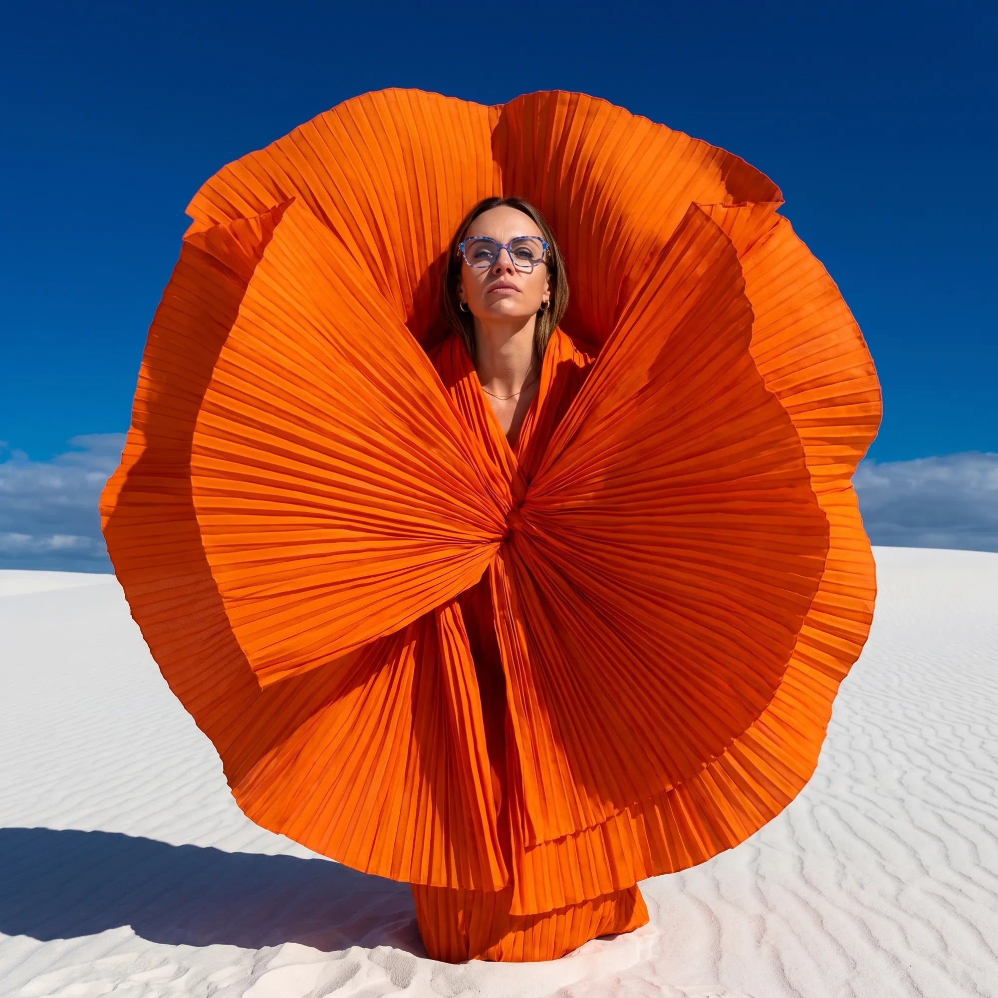 Fiore 1030 eyeglasses in blue pink, worn by a model – campaign portrait, sculptural orange pleated fan on white dunes
