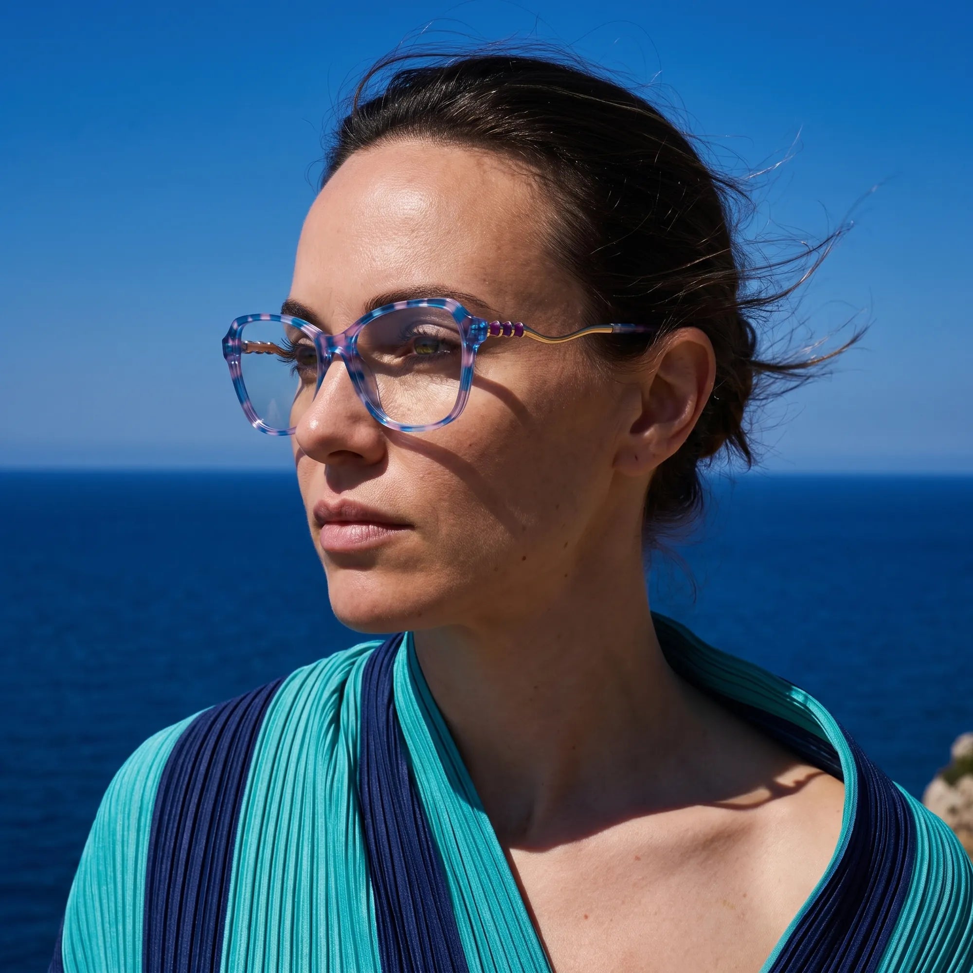 Fiore 1030 eyeglasses in blue pink, worn by a model – campaign portrait, windswept portrait over the deep blue sea
