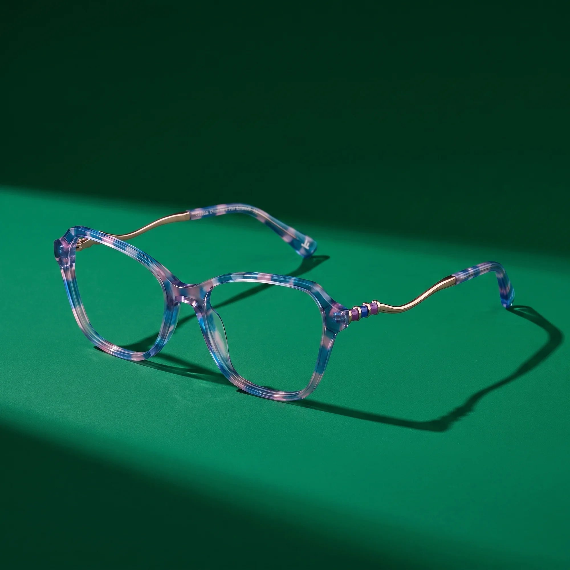 Fiore 1030 eyeglasses in blue pink – editorial still life on a saturated emerald set