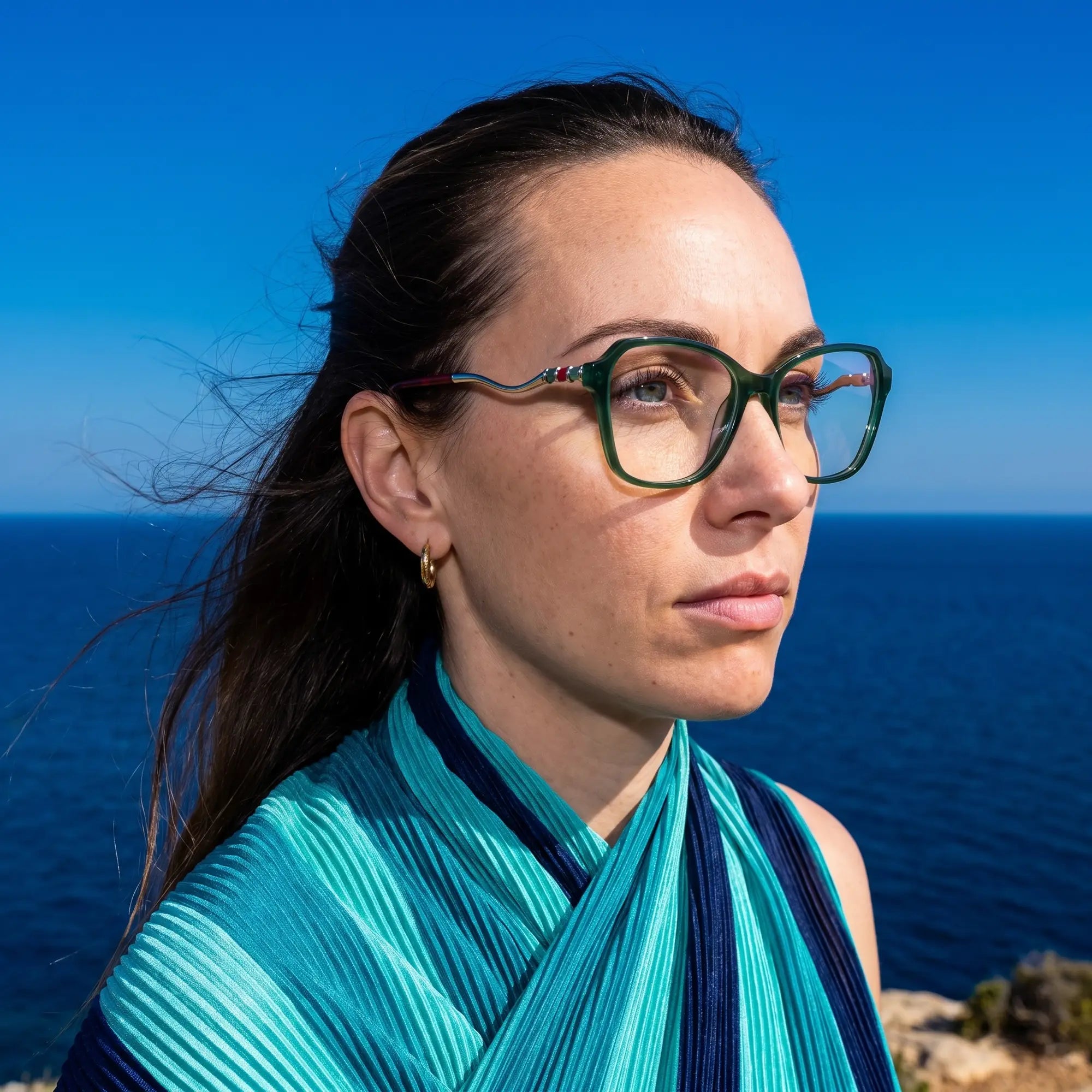Fiore 1030 eyeglasses in green, worn by a model – campaign portrait, windswept portrait over the deep blue sea