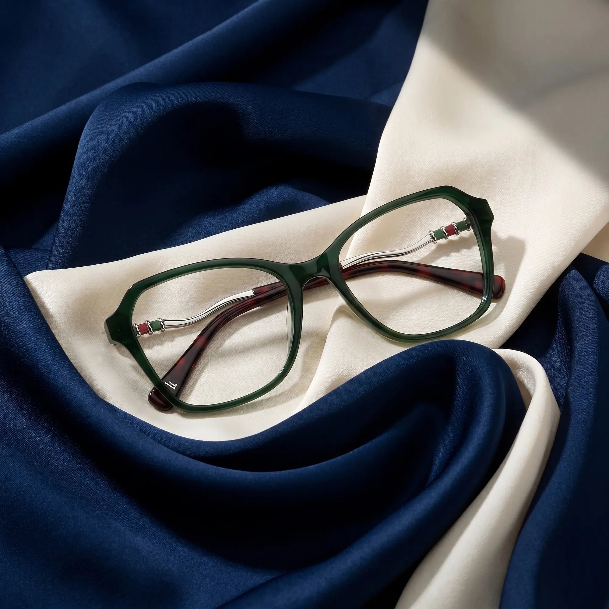 Fiore 1030 eyeglasses in green – resting on draped midnight blue and ivory silk