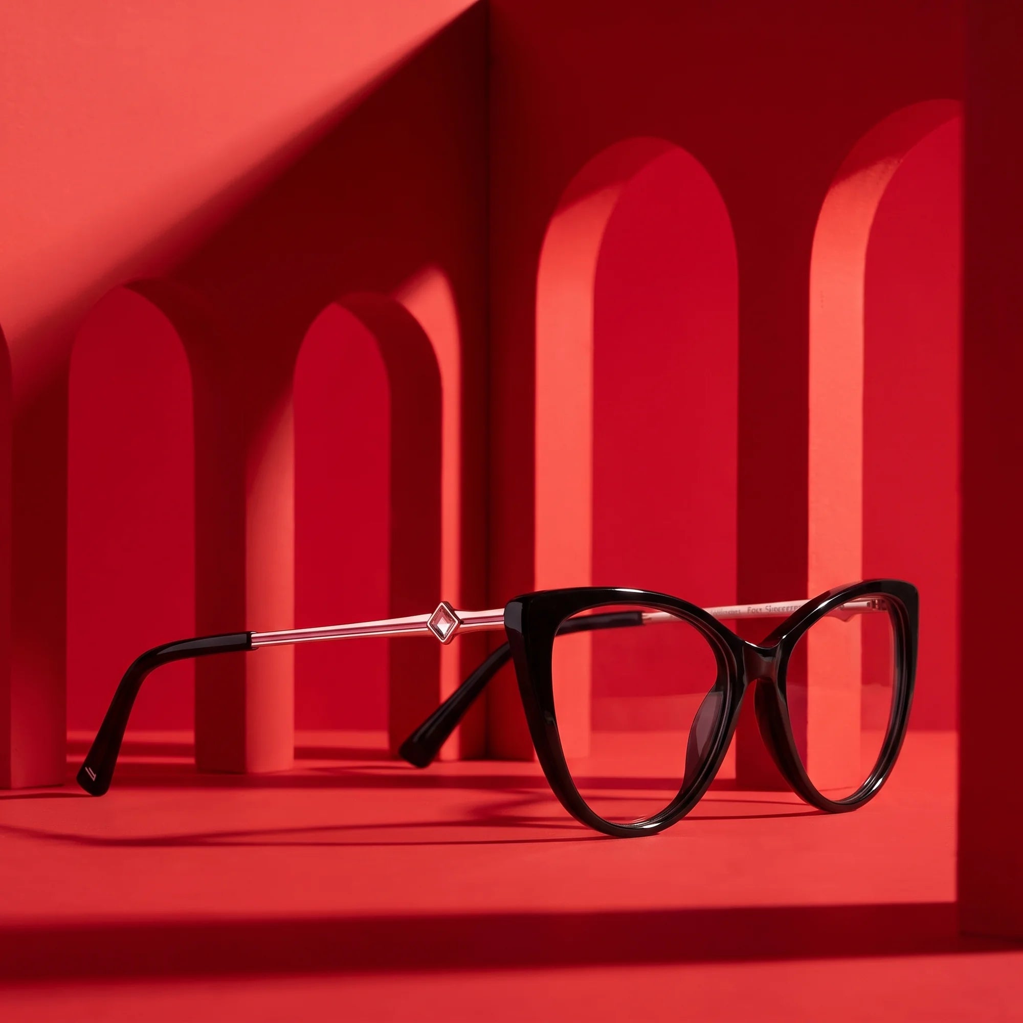 Fiore 1031 eyeglasses in black – displayed on a vivid red podium among arches