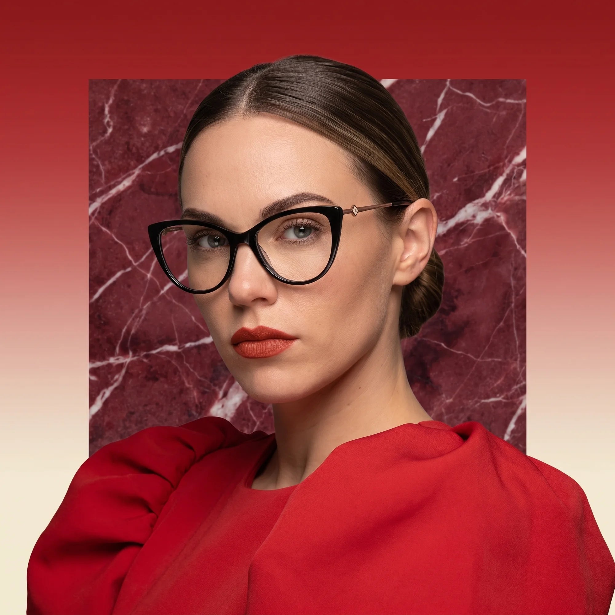 Fiore 1031 eyeglasses in black, worn by a model – campaign portrait, red marble backdrop and draped scarlet dress
