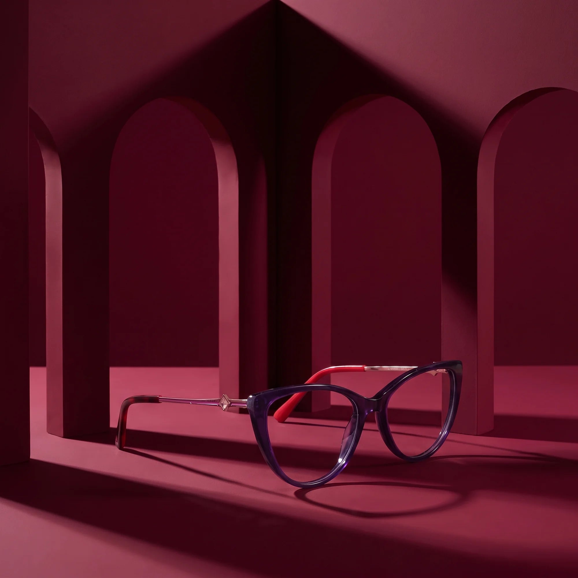 Fiore 1031 eyeglasses in purple green – still life among monochrome burgundy arches