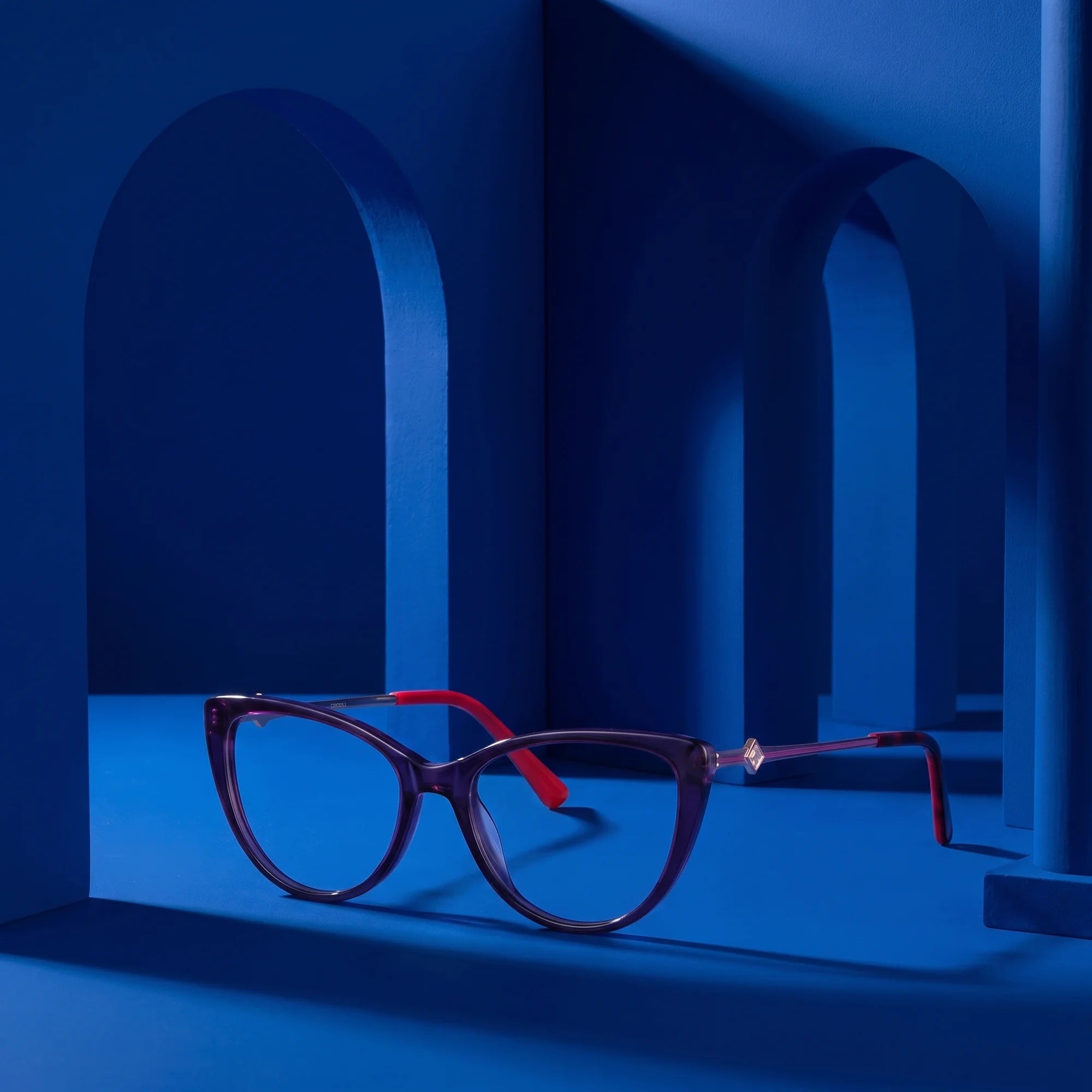 Fiore 1031 eyeglasses in purple green – staged on a sculptural cobalt architecture set