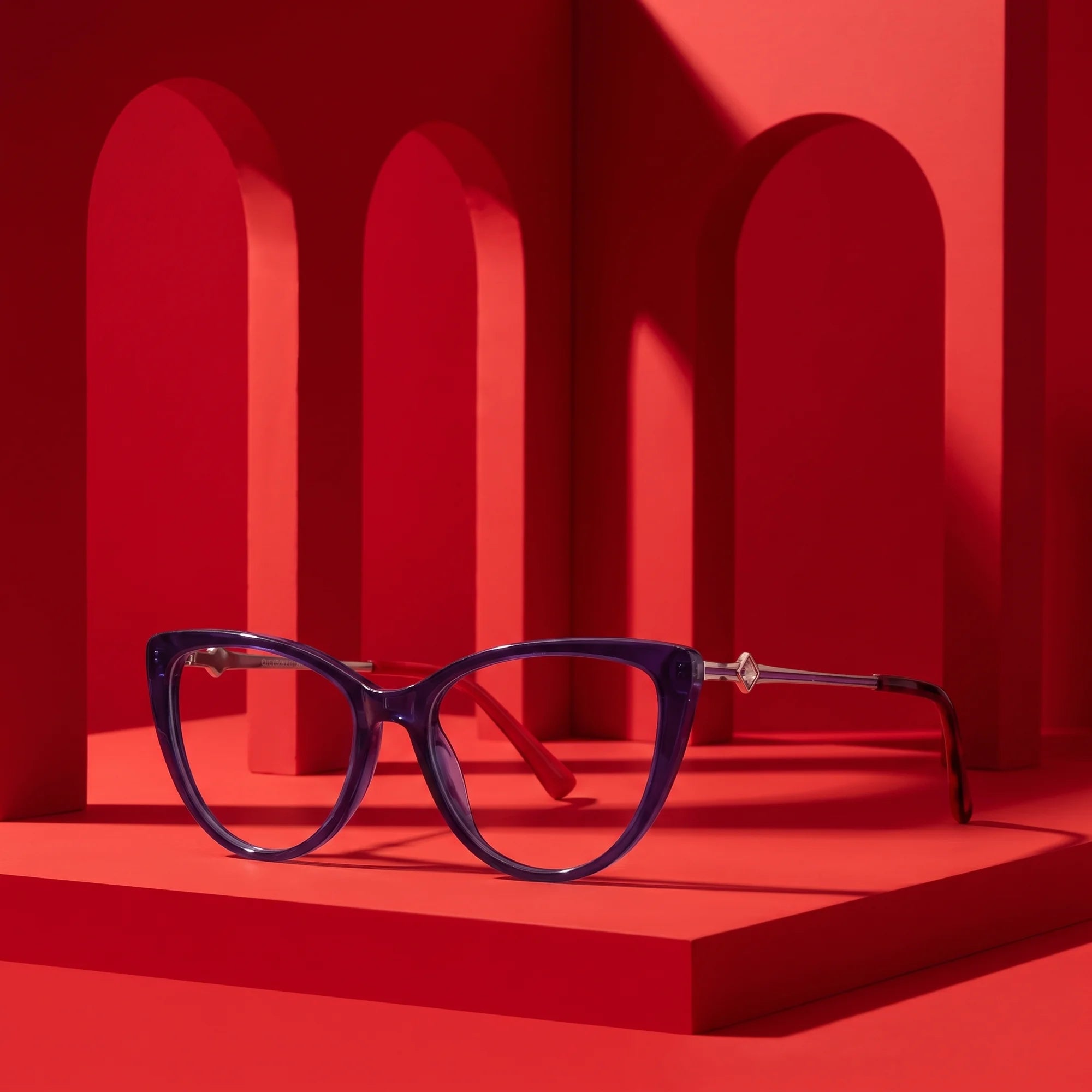 Fiore 1031 eyeglasses in purple green – displayed on a vivid red podium among arches