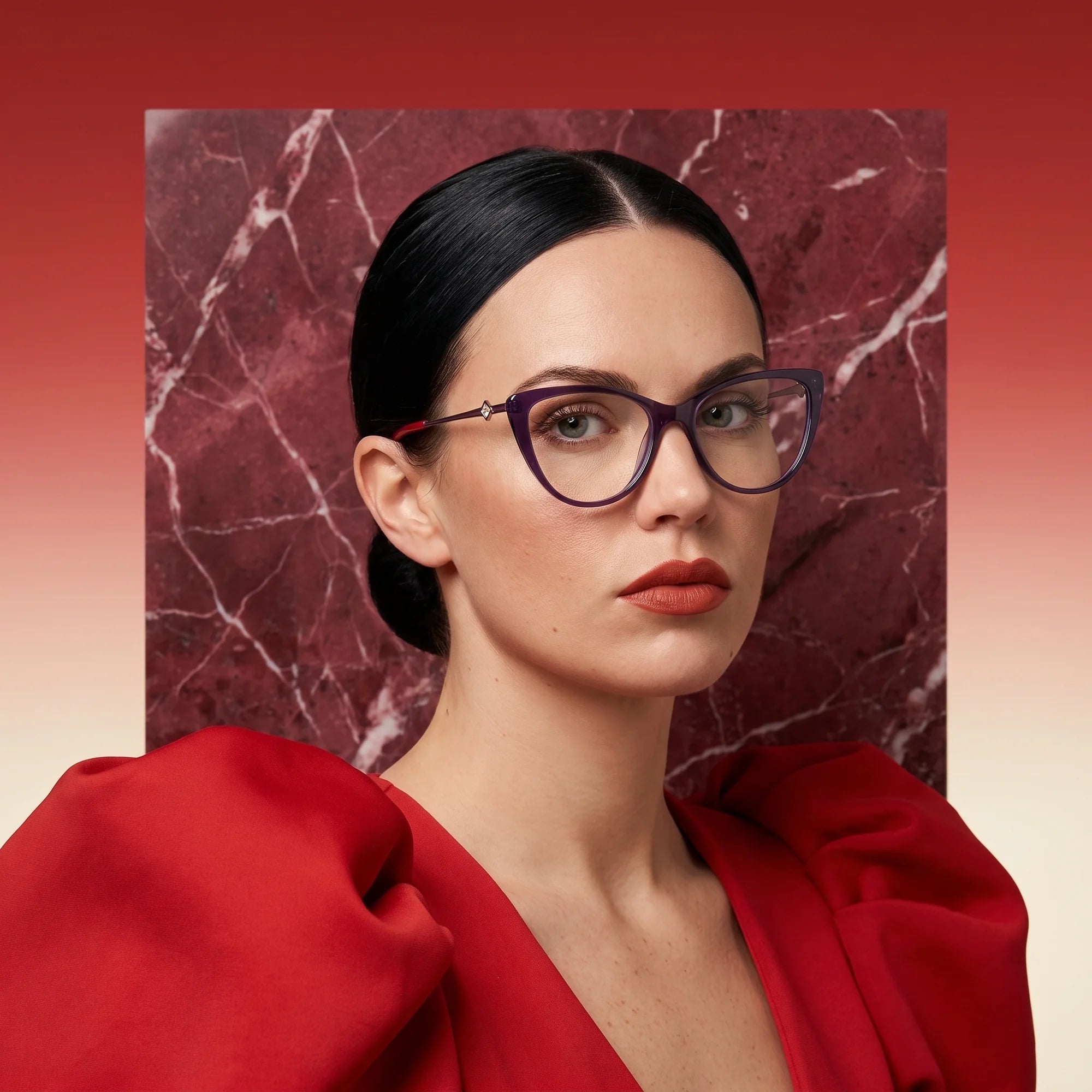 Fiore 1031 eyeglasses in purple green, worn by a model – campaign portrait, red marble backdrop and draped scarlet dress