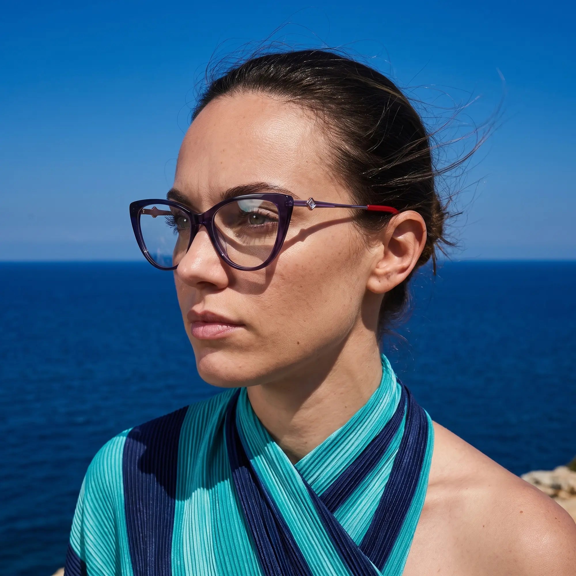 Fiore 1031 eyeglasses in purple green, worn by a model – campaign portrait, windswept portrait over the deep blue sea