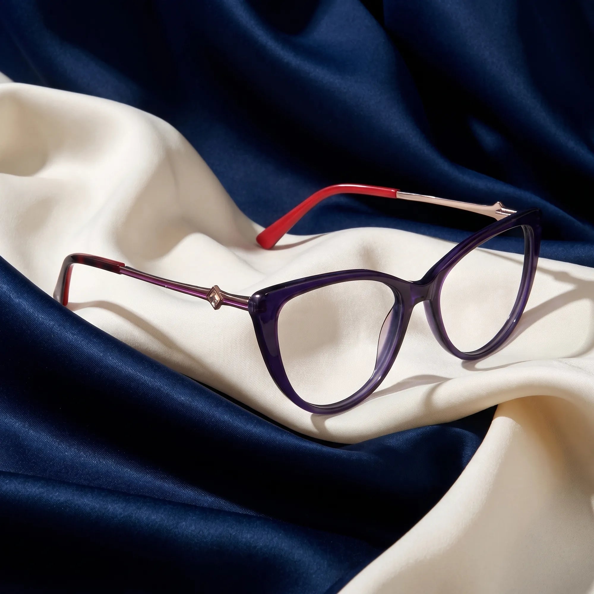 Fiore 1031 eyeglasses in purple green – resting on draped midnight blue and ivory silk