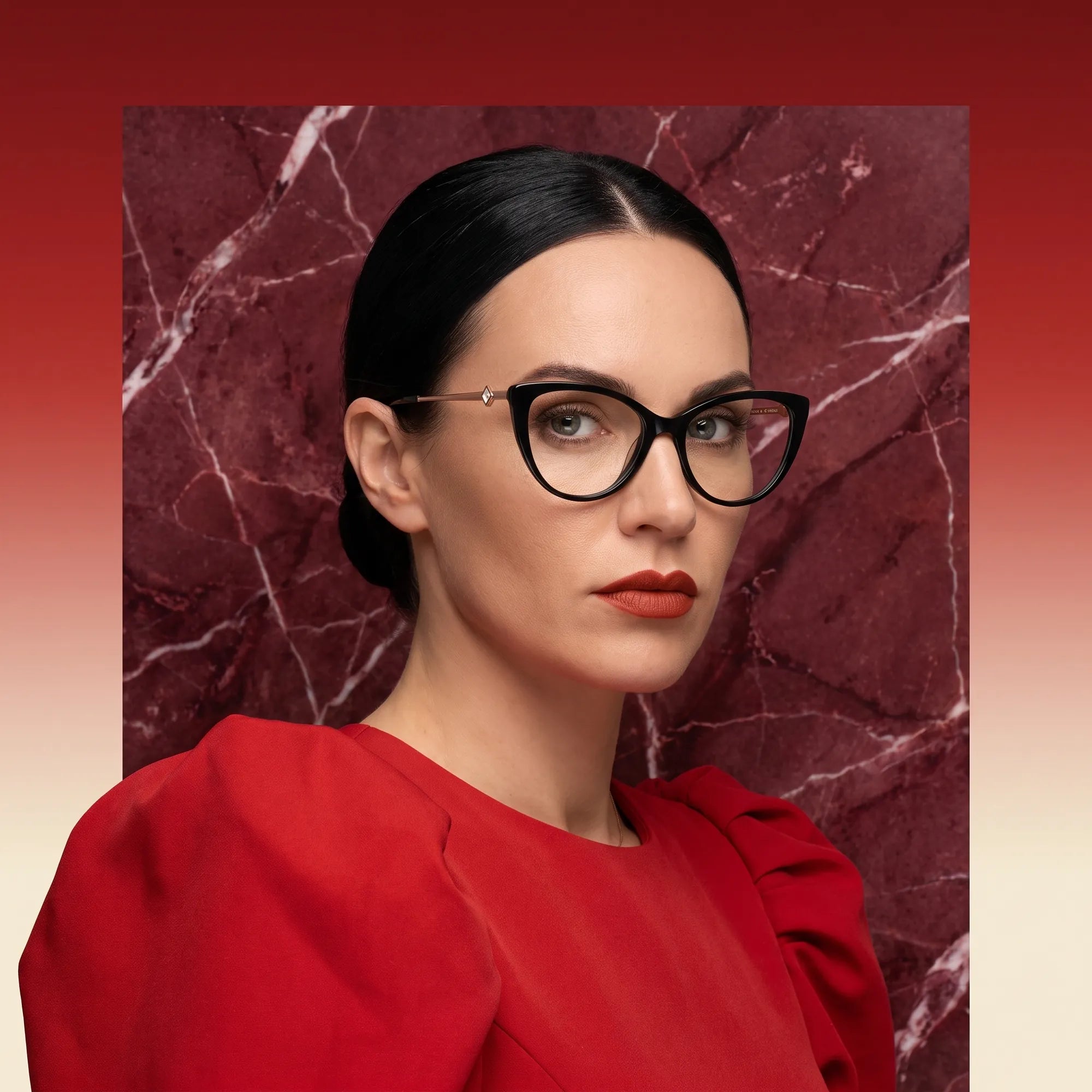 Fiore 1031 eyeglasses in green, worn by a model – campaign portrait, red marble backdrop and draped scarlet dress