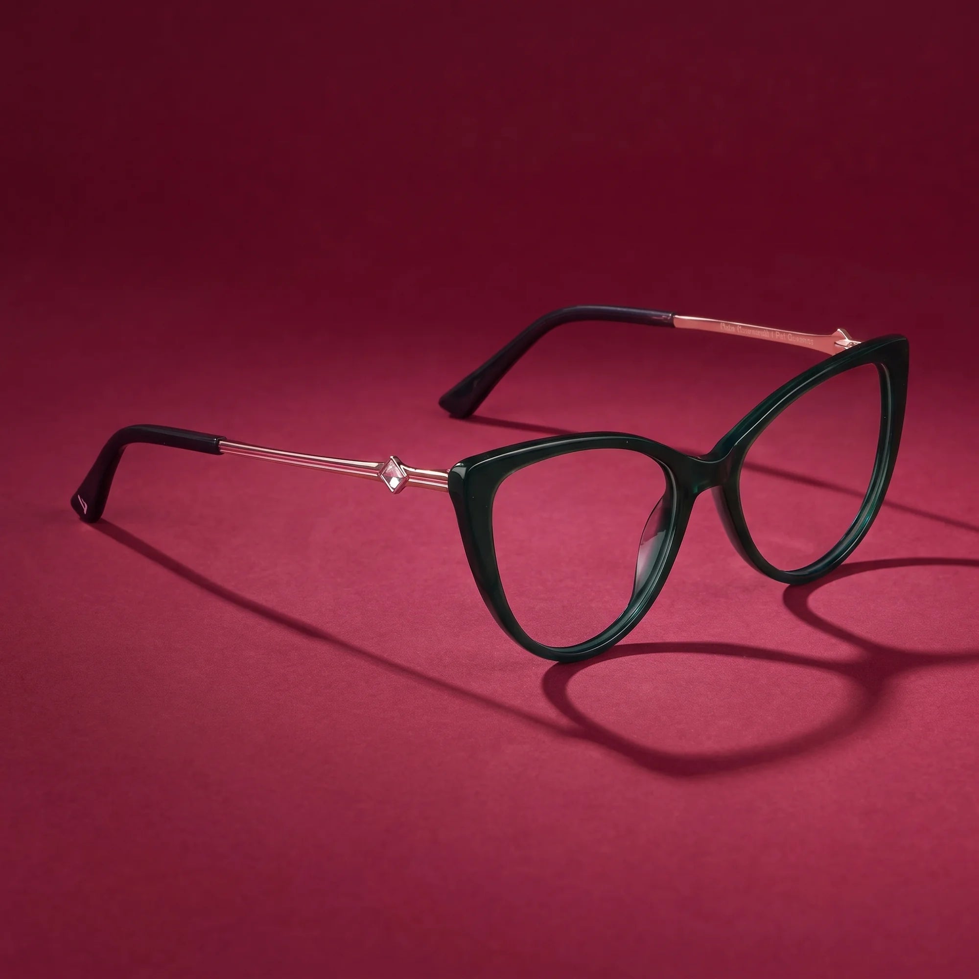 Fiore 1031 eyeglasses in green – still life on a seamless burgundy studio backdrop