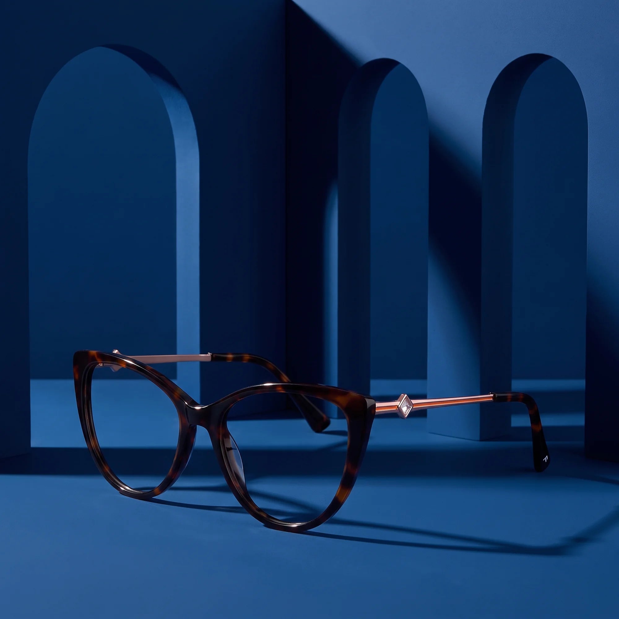 Fiore 1031 eyeglasses in tortoiseshell – displayed on a midnight blue podium among arches