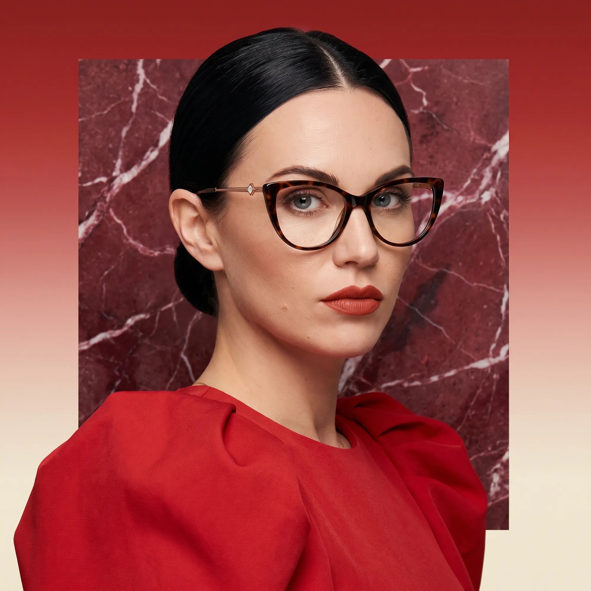 Fiore 1031 eyeglasses in tortoiseshell, worn by a model – campaign portrait, red marble backdrop and draped scarlet dress