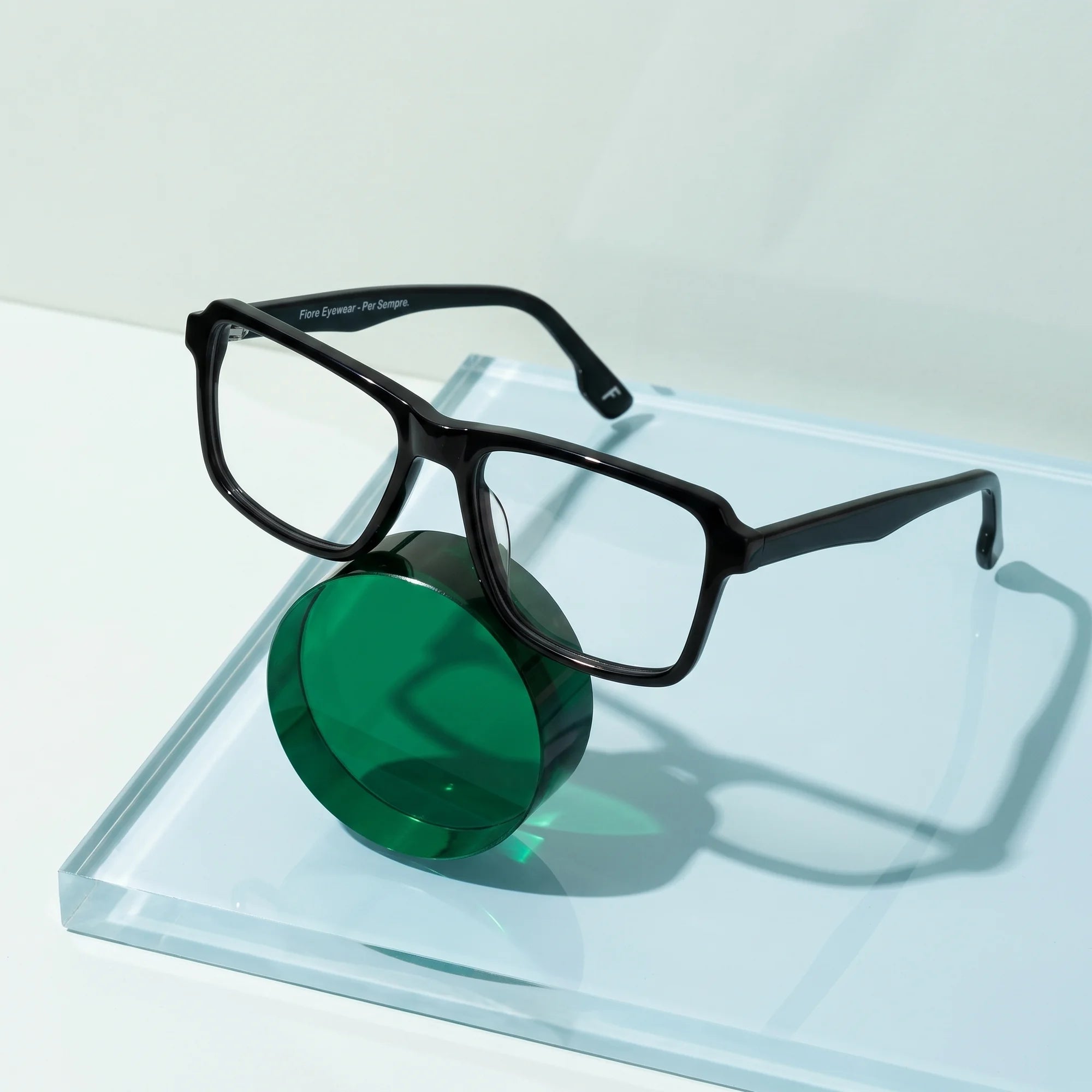 Fiore 1038 eyeglasses in black – on a cobalt acrylic disc in soft daylight