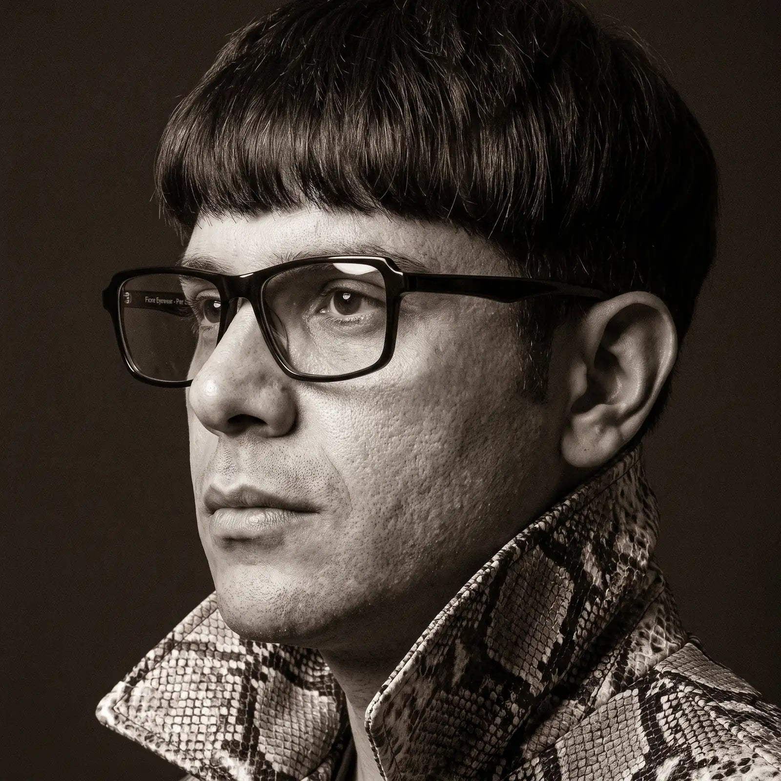 Fiore 1038 eyeglasses in black, worn by a model – campaign portrait, monochrome studio portrait, red graphic accents