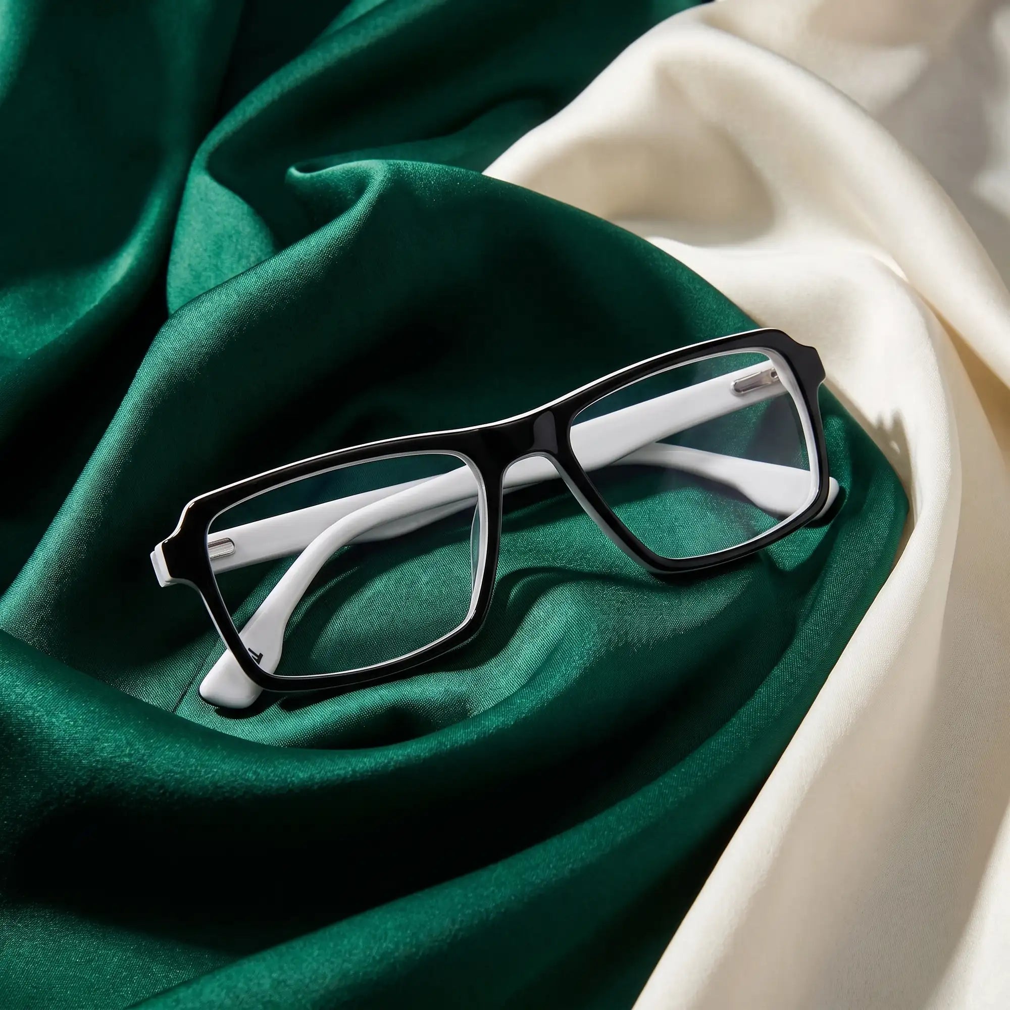 Fiore 1038 eyeglasses in black white – resting on draped emerald and ivory silk