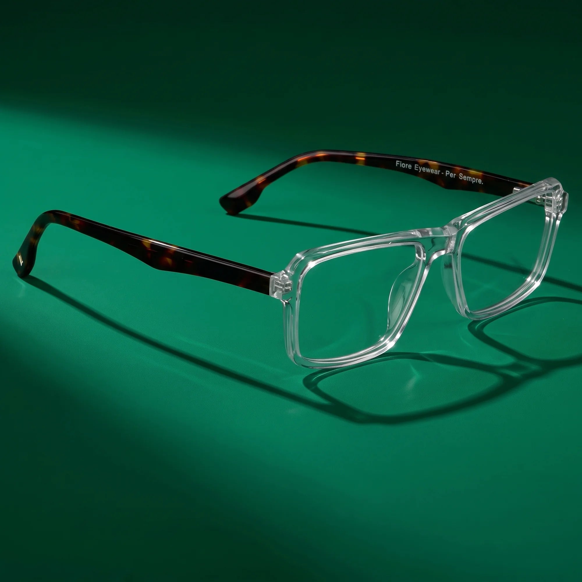 Fiore 1038 eyeglasses in transparent – editorial still life on a saturated emerald set
