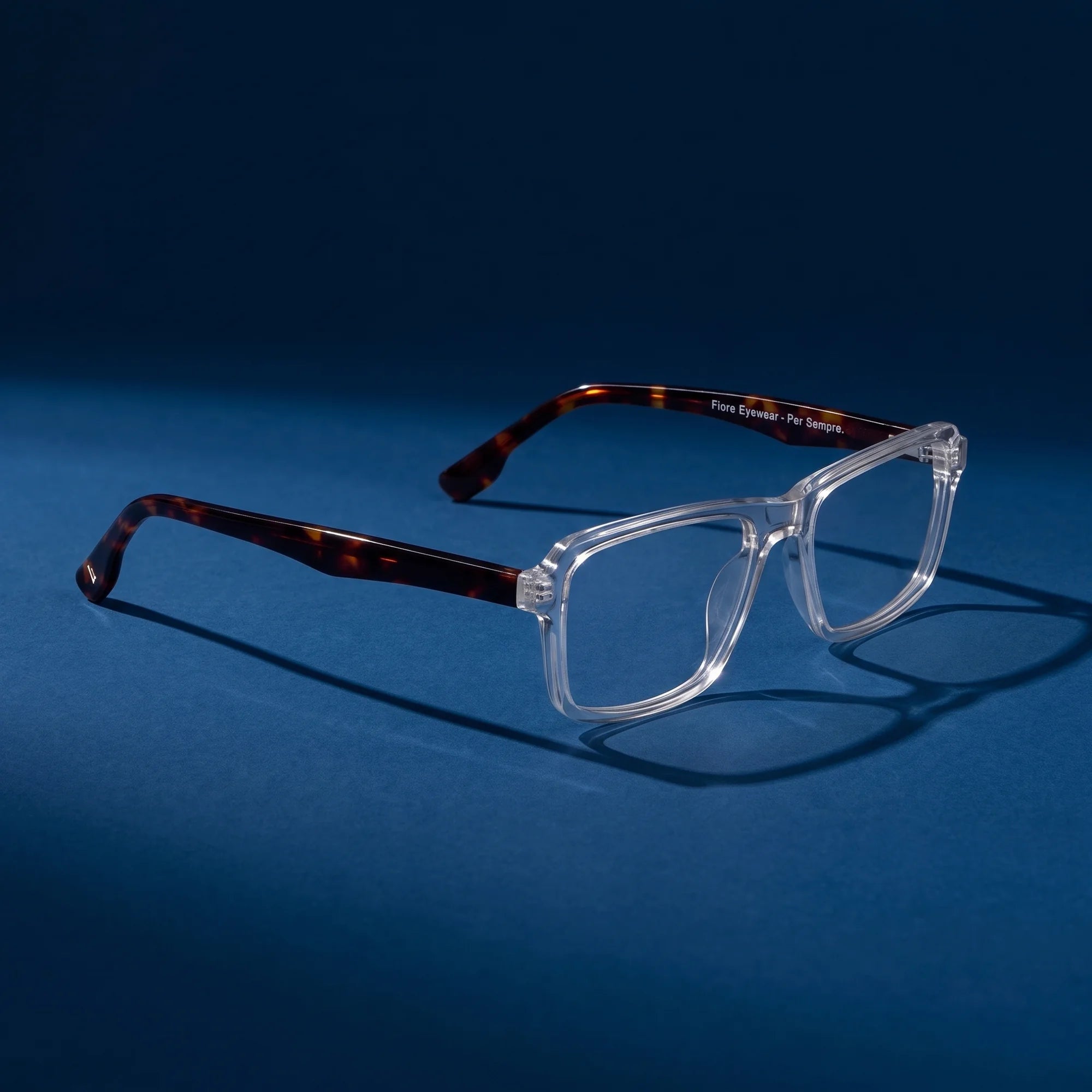 Fiore 1038 eyeglasses in transparent – hero still life against a deep midnight blue backdrop