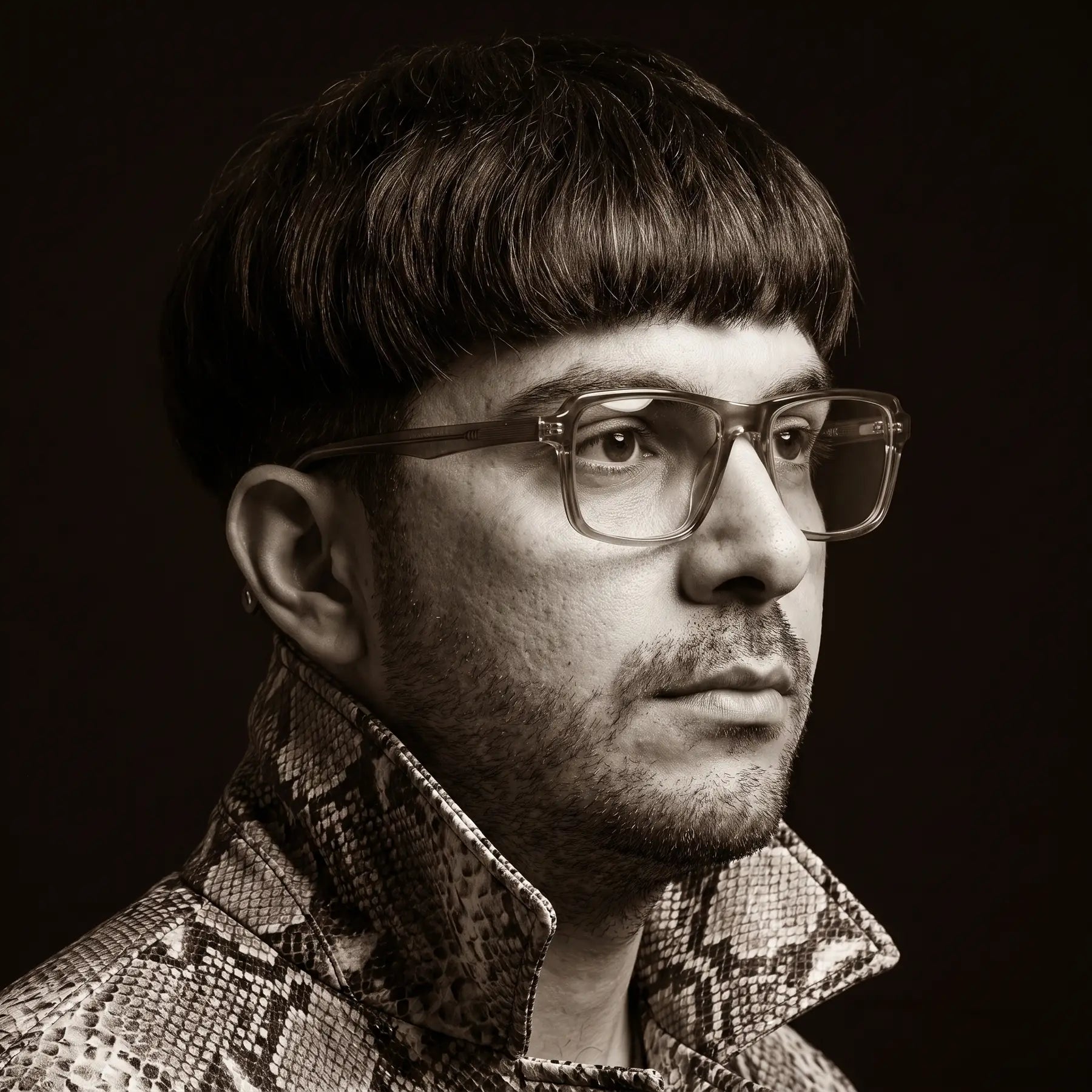 Fiore 1038 eyeglasses in brown, worn by a model – campaign portrait, monochrome studio portrait, red graphic accents