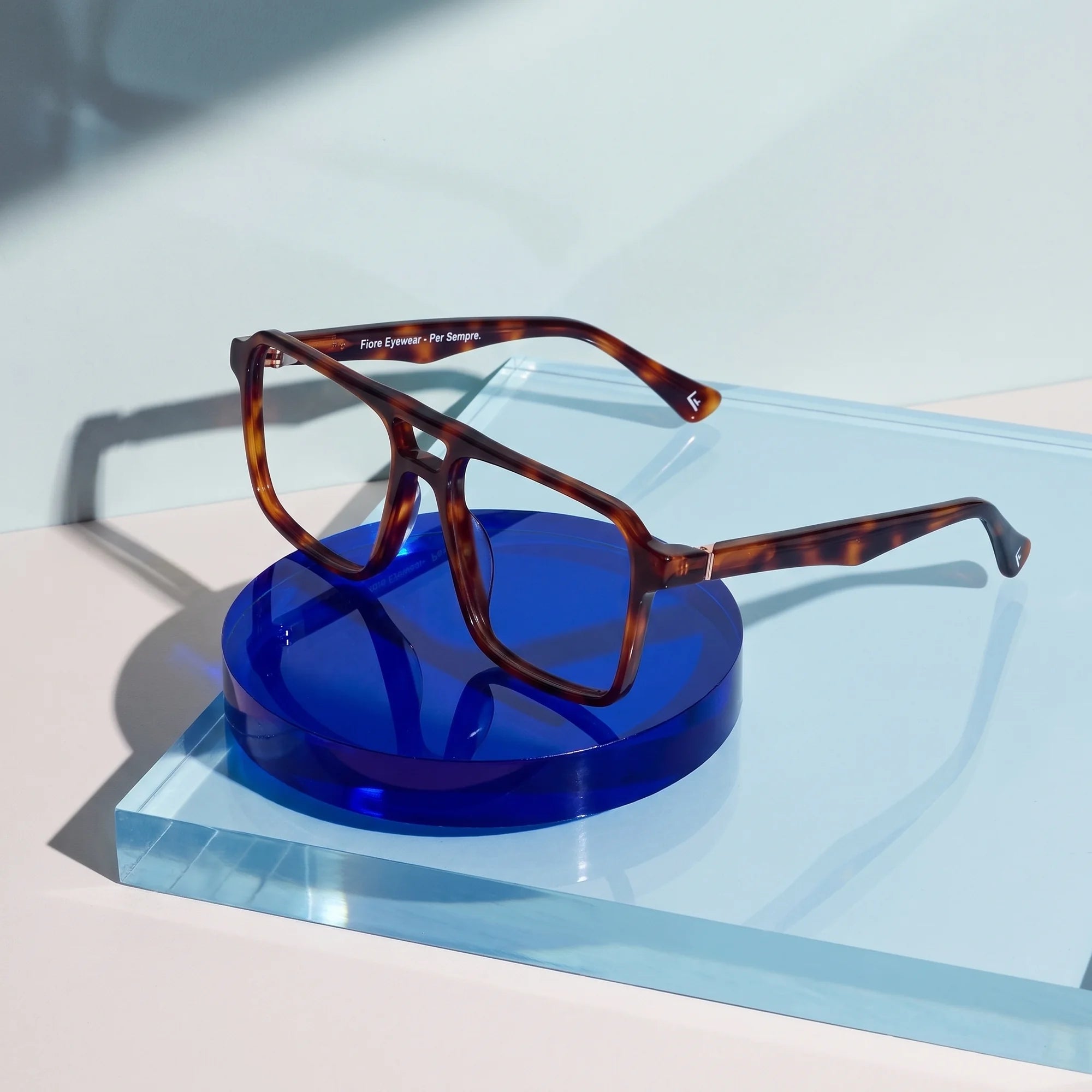 Fiore 1039 eyeglasses in tortoiseshell – on a cobalt acrylic disc in soft daylight