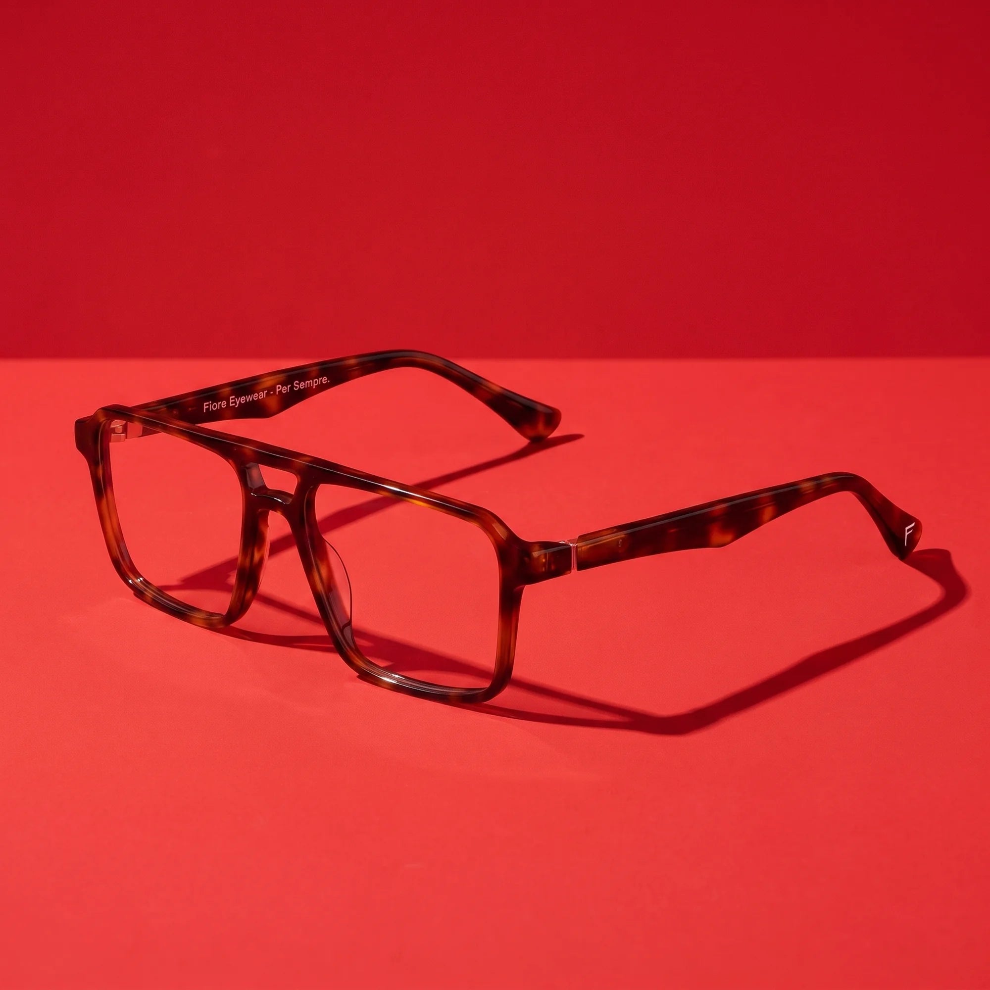 Fiore 1039 eyeglasses in tortoiseshell – hero still life against a deep vivid red backdrop