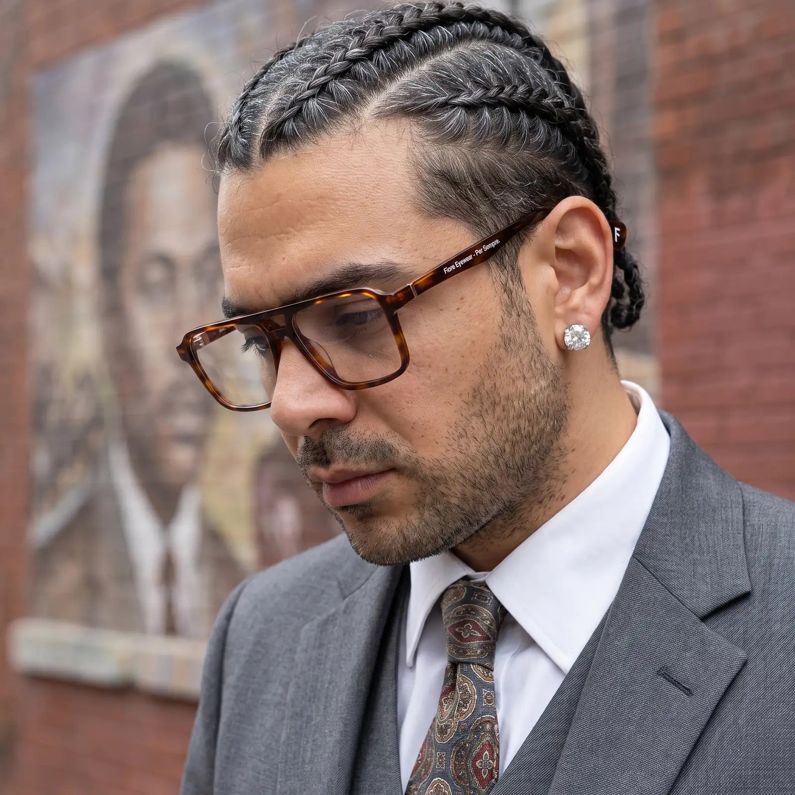 Fiore 1039 eyeglasses in tortoiseshell, worn by a model – campaign portrait, pensive portrait against a painted brick mural