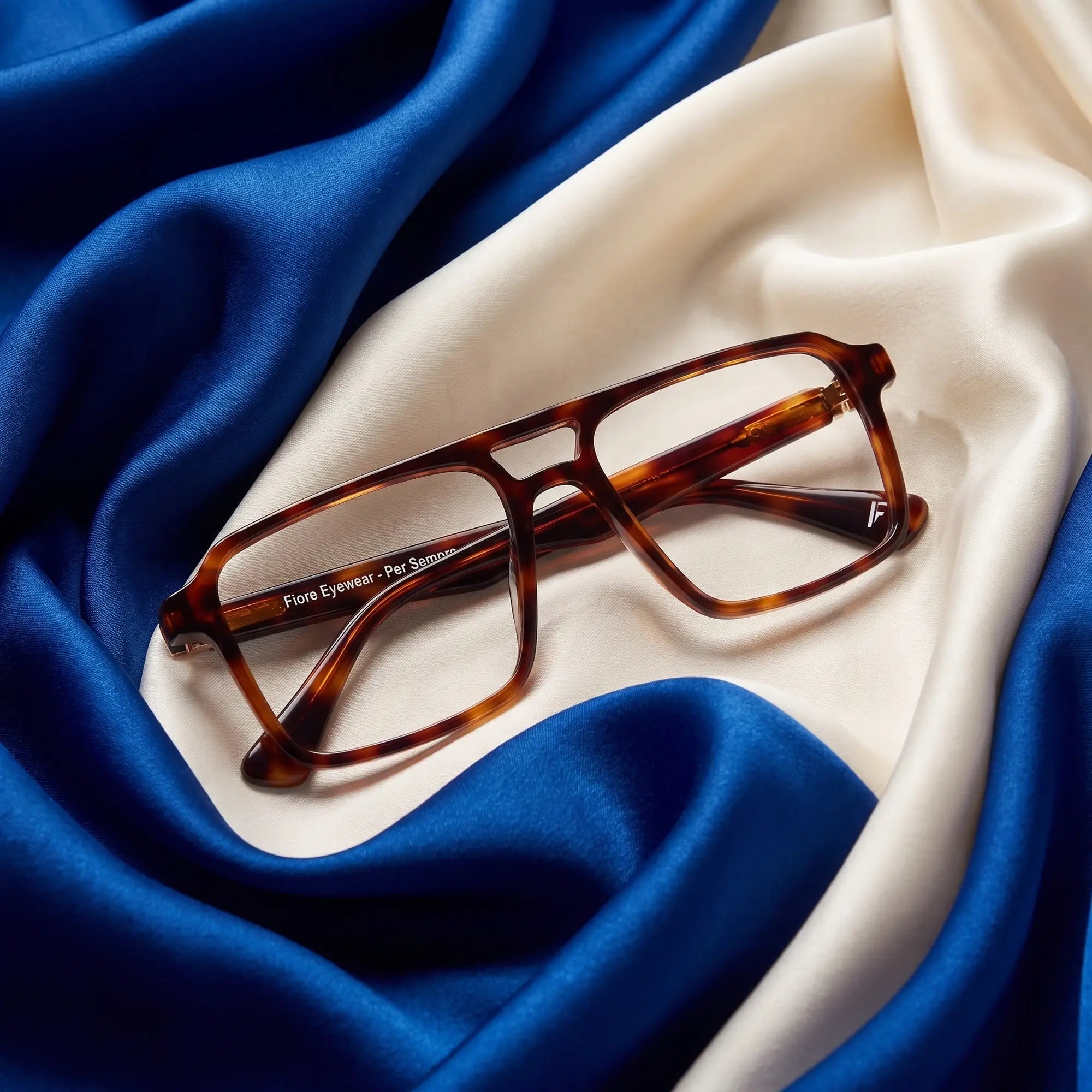 Fiore 1039 eyeglasses in tortoiseshell – resting on draped cobalt and ivory silk