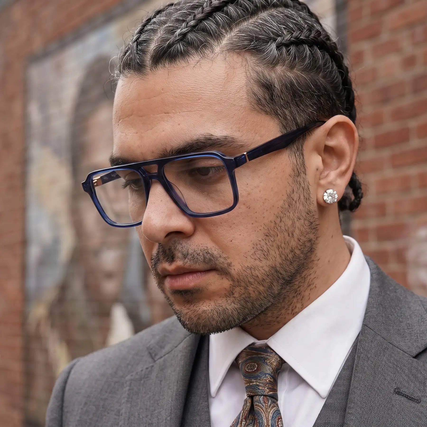 Fiore 1039 eyeglasses in blue, worn by a model – campaign portrait, pensive portrait against a painted brick mural