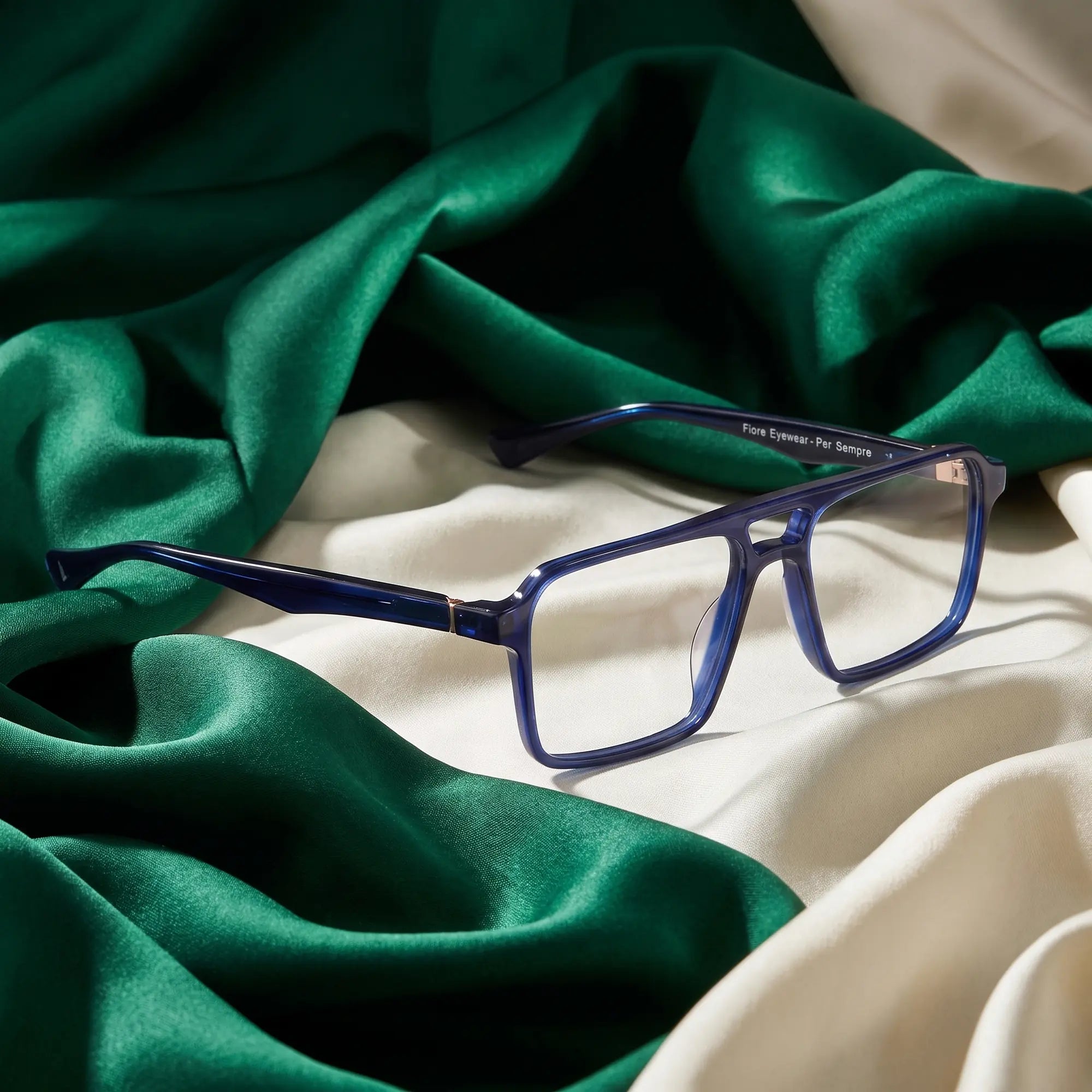 Fiore 1039 eyeglasses in blue – resting on draped emerald and ivory silk