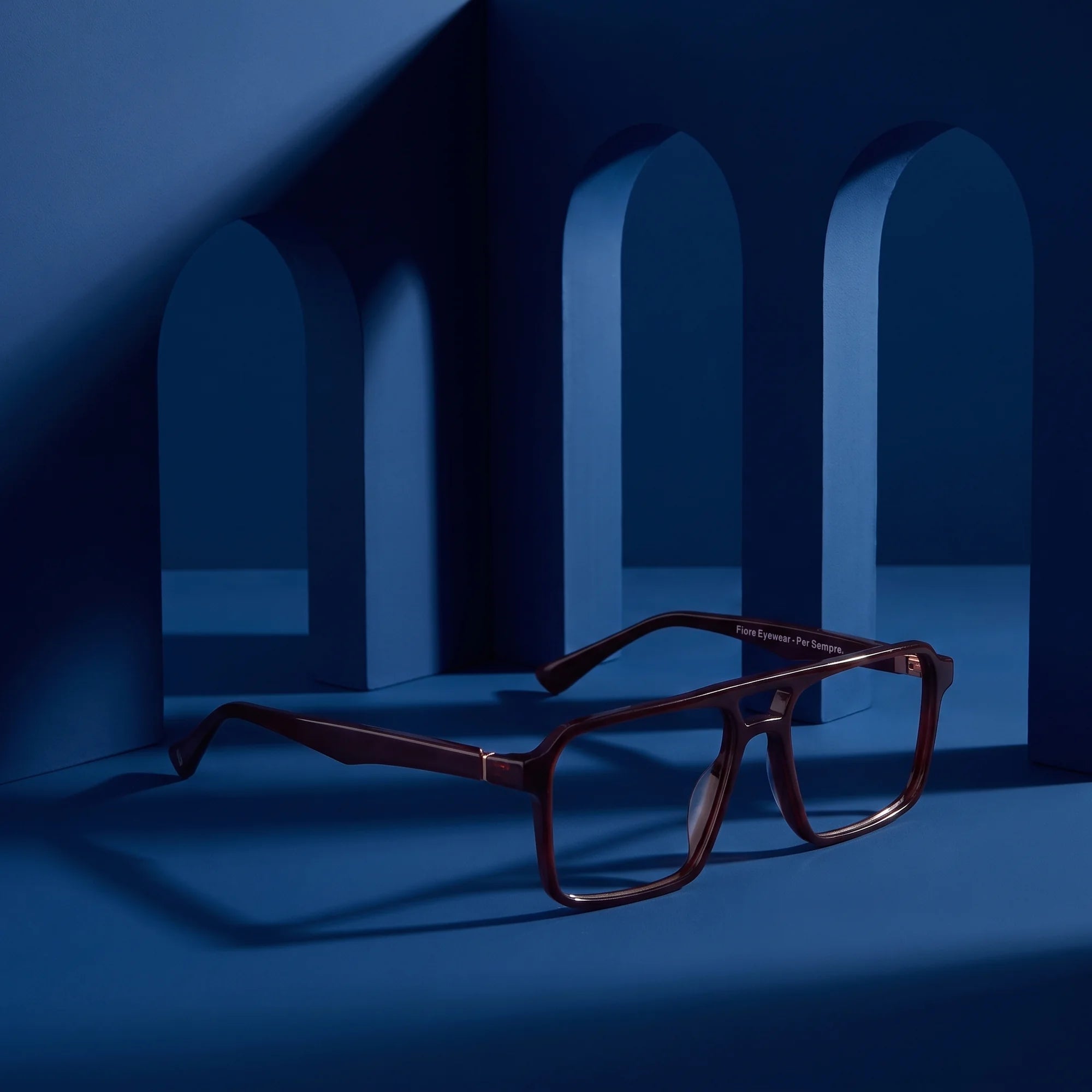 Fiore 1039 eyeglasses in brown – staged on a sculptural midnight blue architecture set