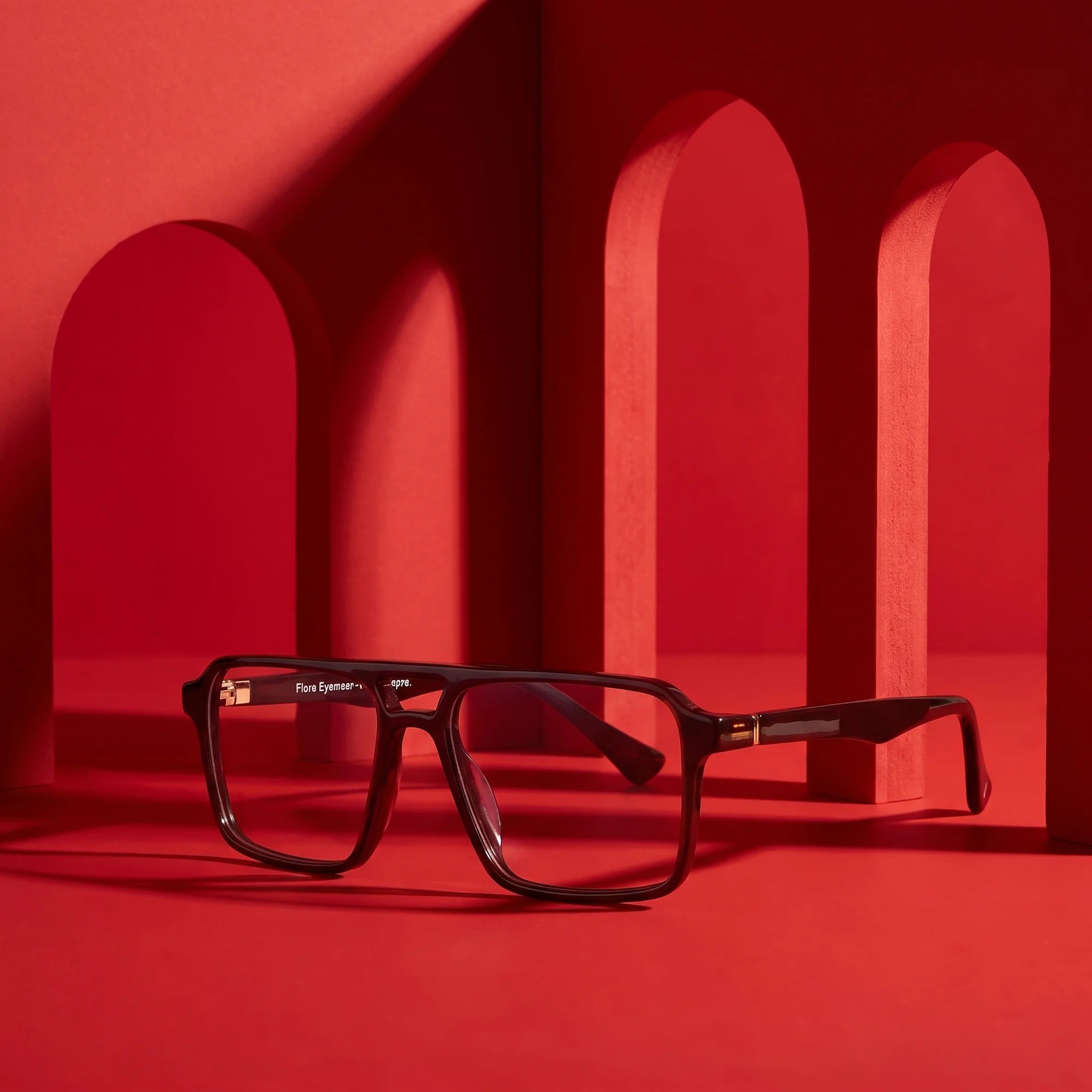 Fiore 1039 eyeglasses in brown – displayed on a vivid red podium among arches