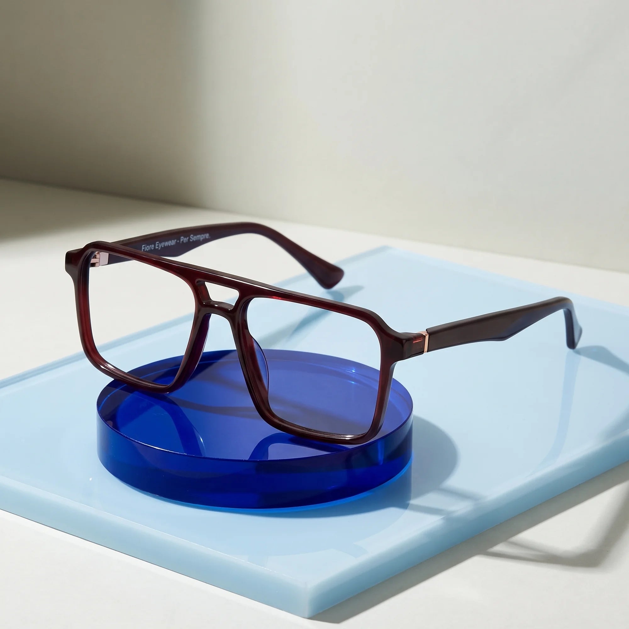 Fiore 1039 eyeglasses in brown – on a cobalt acrylic disc in soft daylight