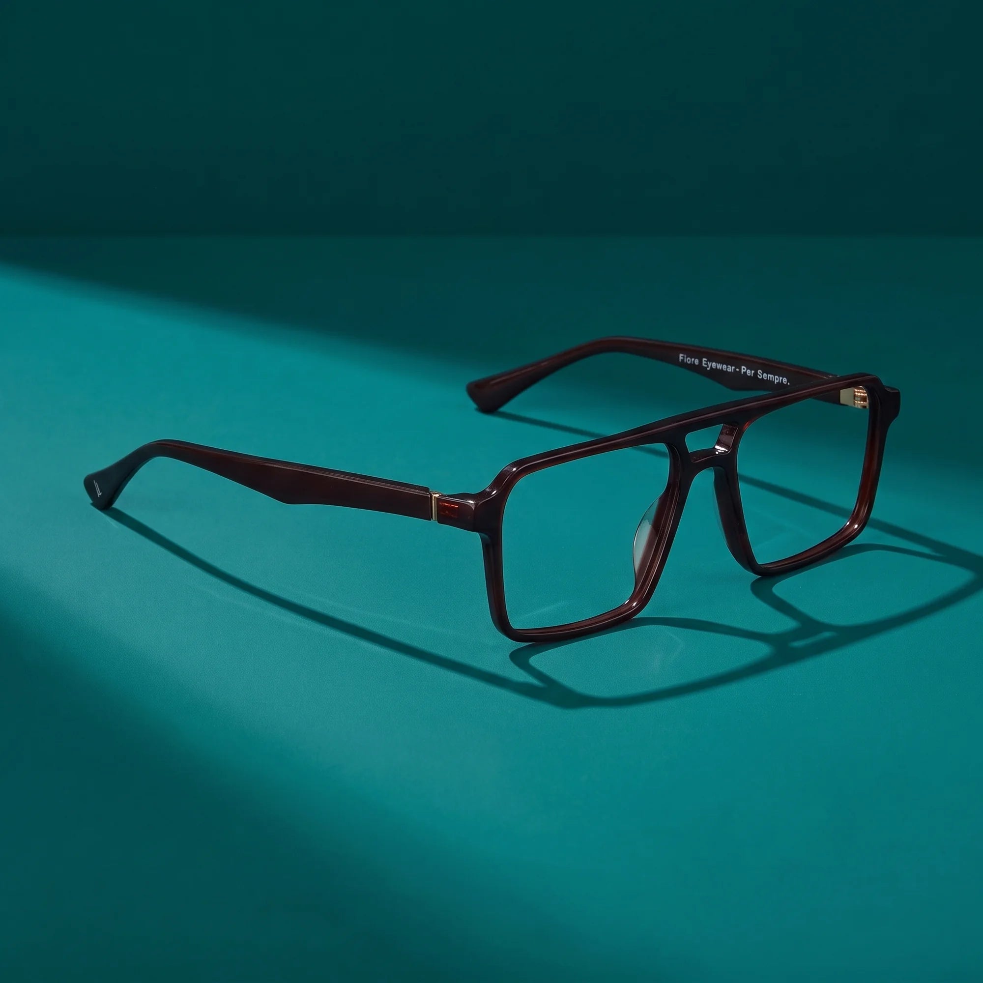 Fiore 1039 eyeglasses in brown – hero still life against a deep teal backdrop