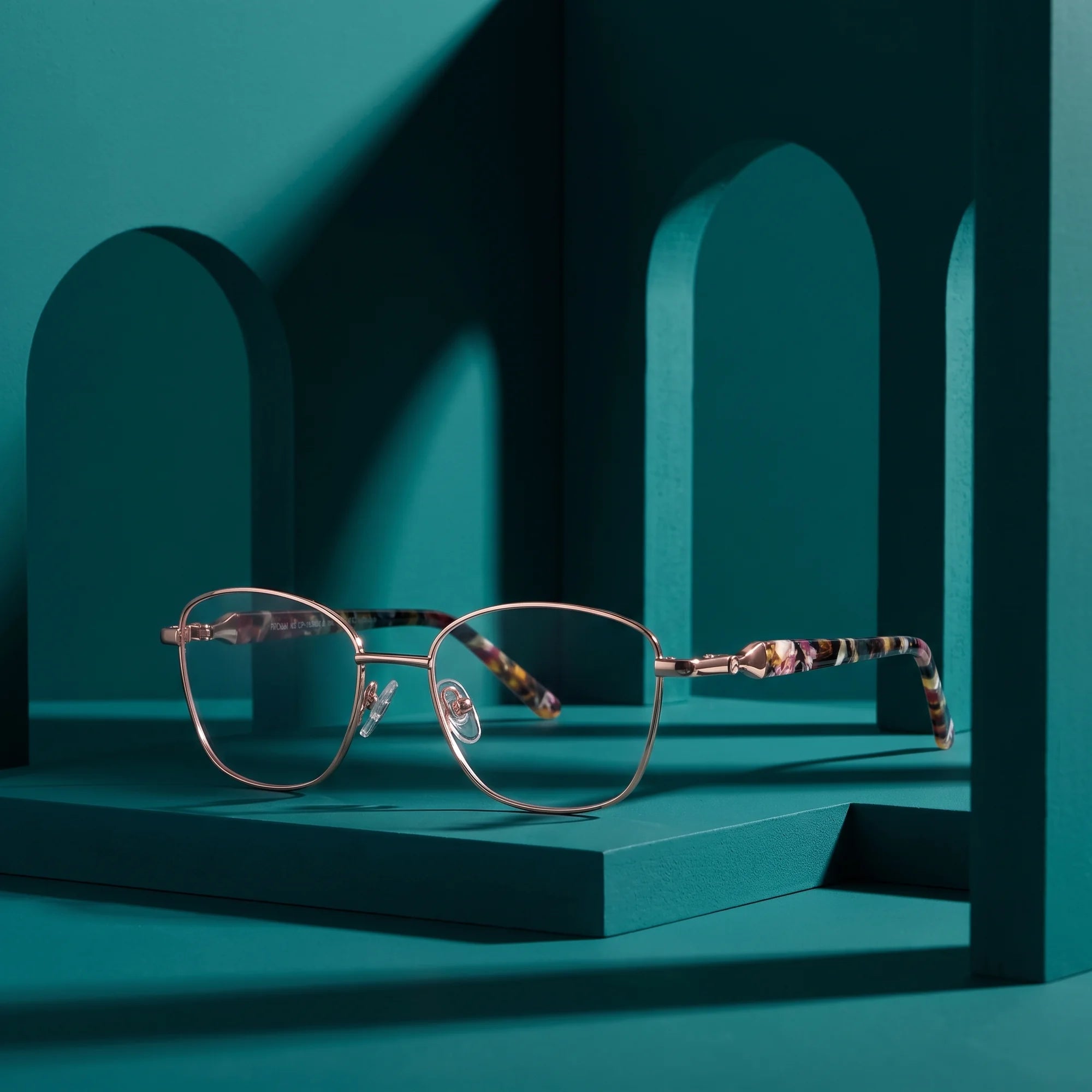 Fiore 2208 eyeglasses in brown gold – staged on a sculptural teal architecture set