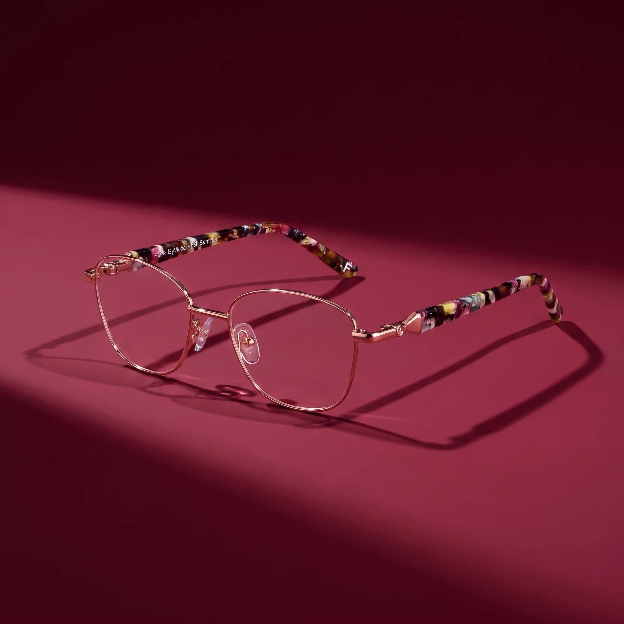 Fiore 2208 eyeglasses in brown gold – editorial still life on a saturated burgundy set