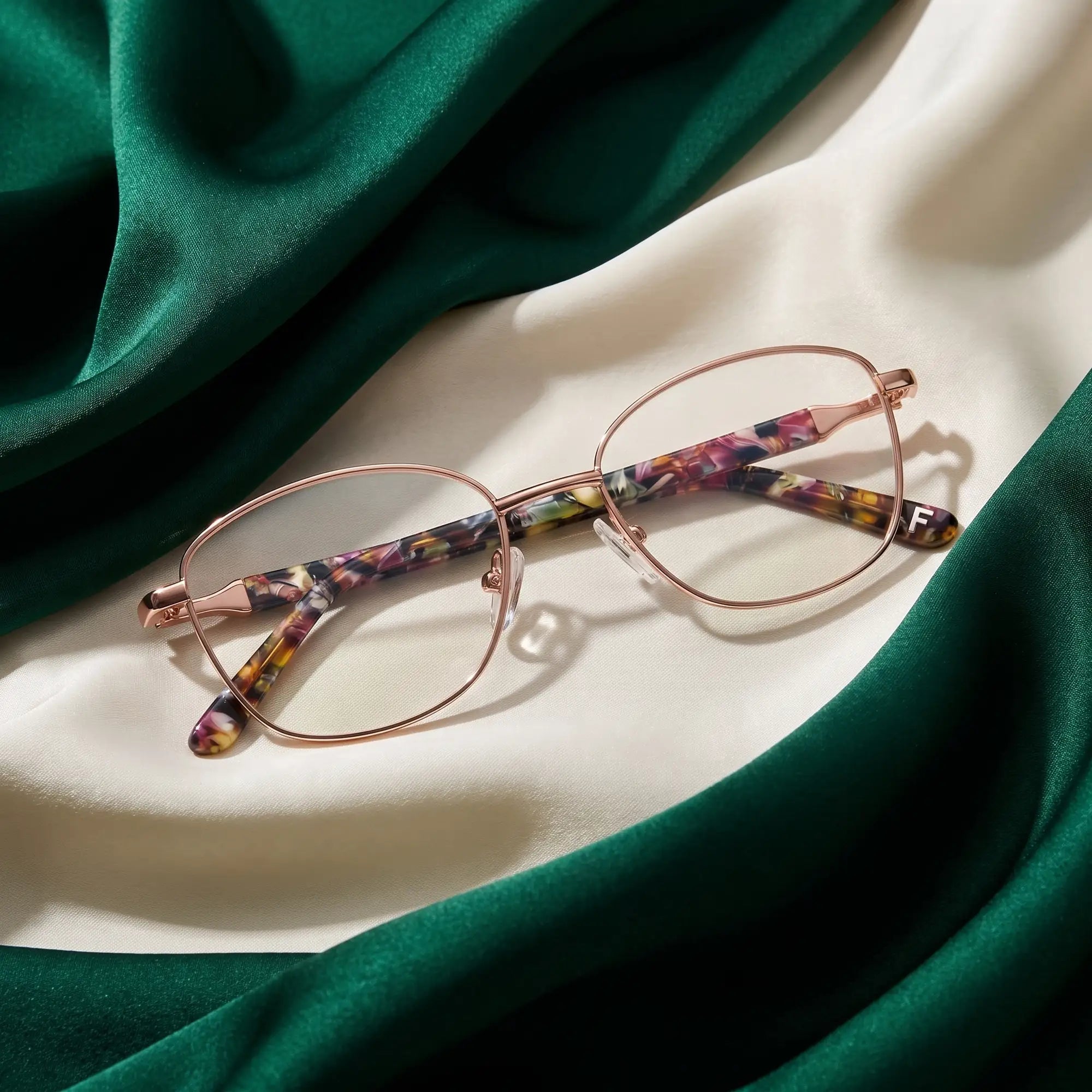Fiore 2208 eyeglasses in brown gold – resting on draped emerald and ivory silk