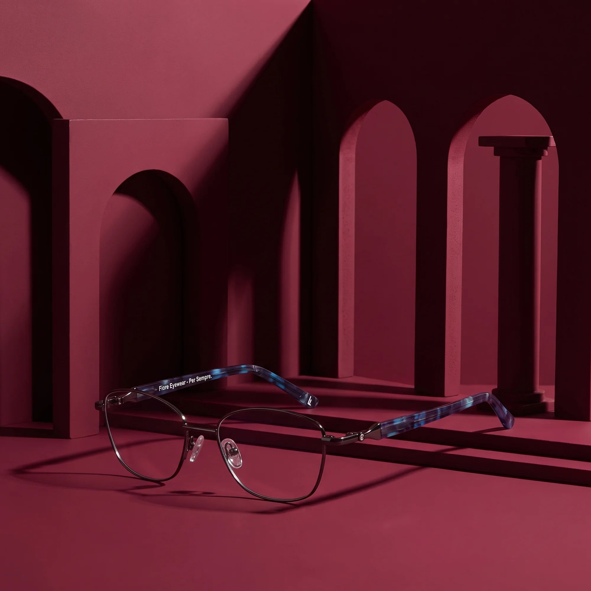 Fiore 2208 eyeglasses in gun blue – staged on a sculptural burgundy architecture set