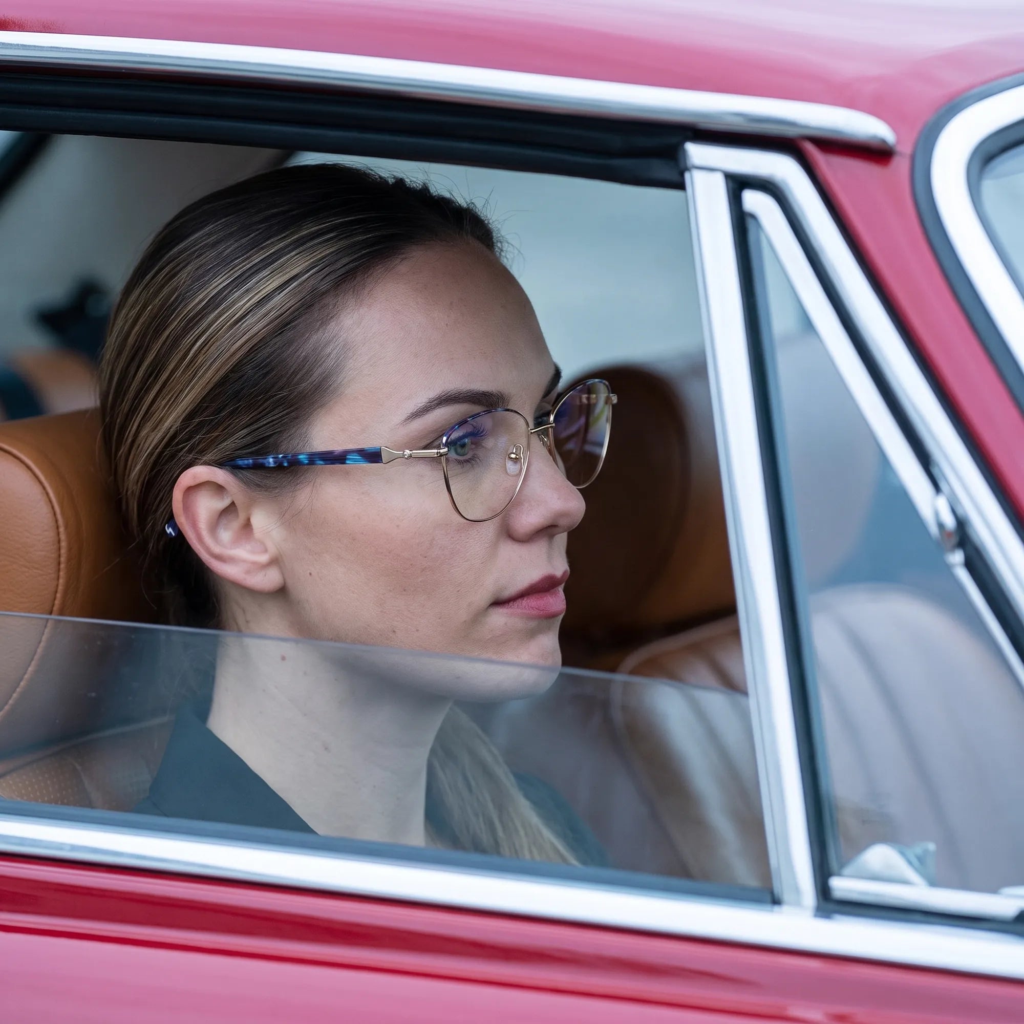 Fiore 2208 eyeglasses in gun blue, worn by a model – campaign portrait, gaze through a classic red car window