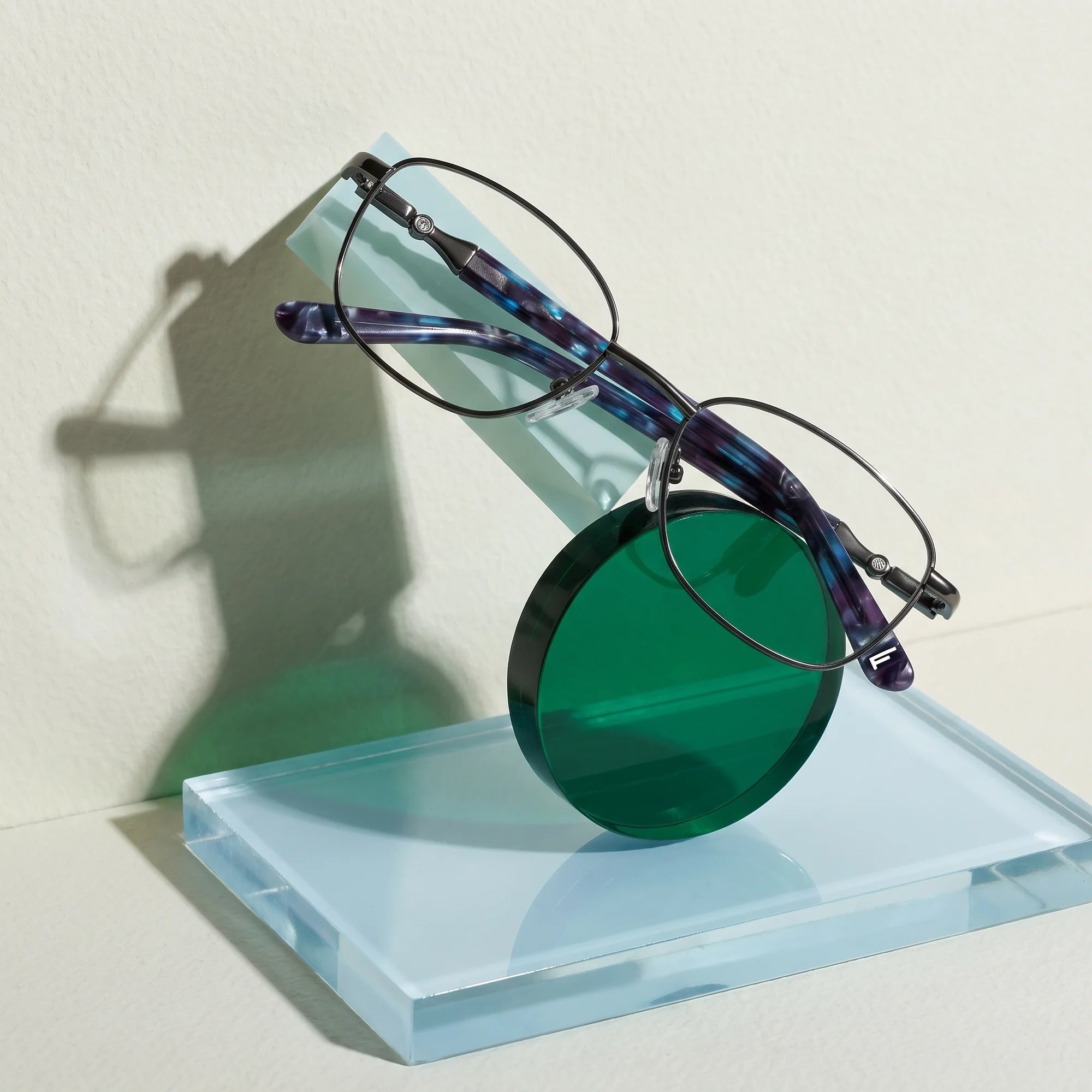 Fiore 2208 eyeglasses in gun blue – on a cobalt acrylic disc in soft daylight