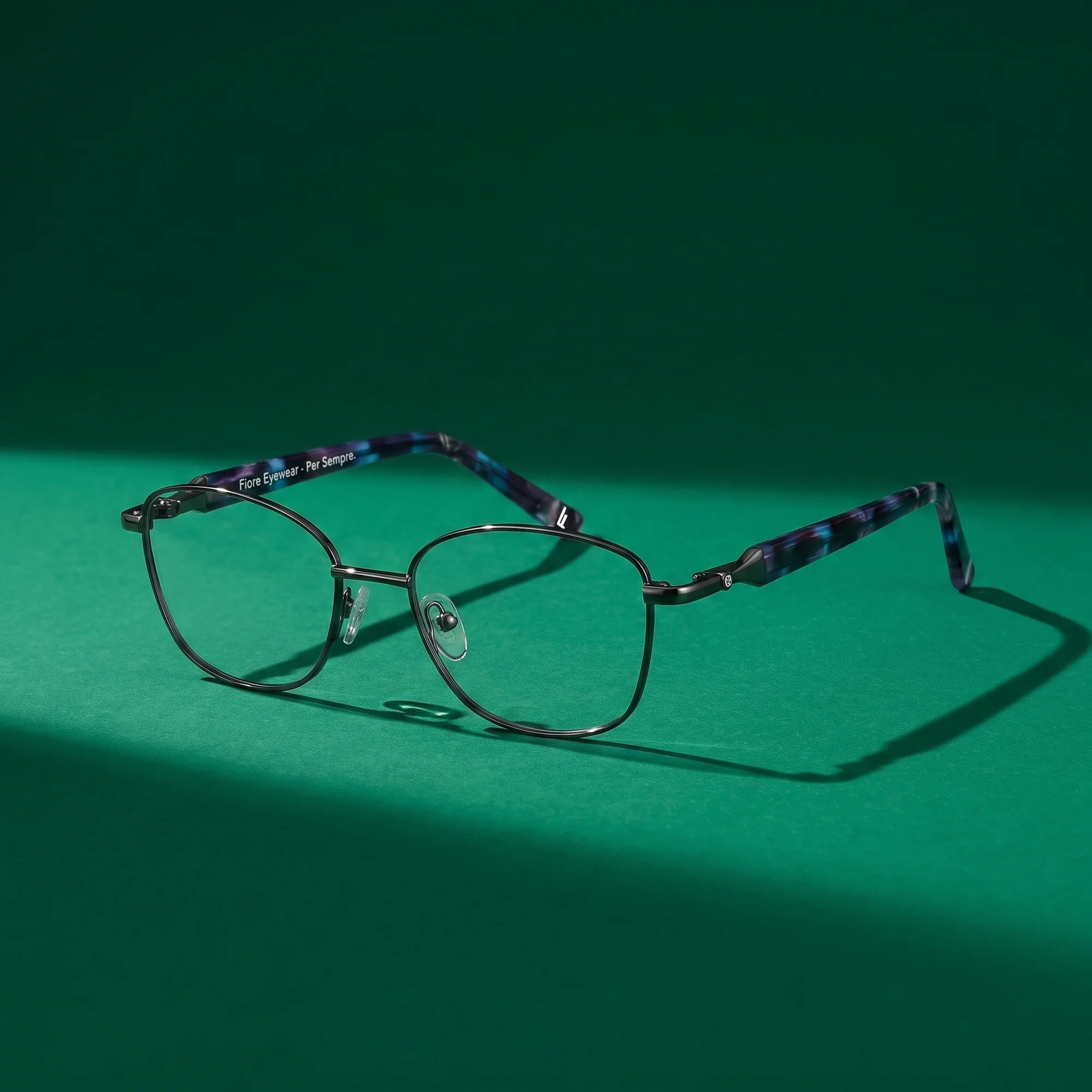 Fiore 2208 eyeglasses in gun blue – still life on a seamless emerald studio backdrop