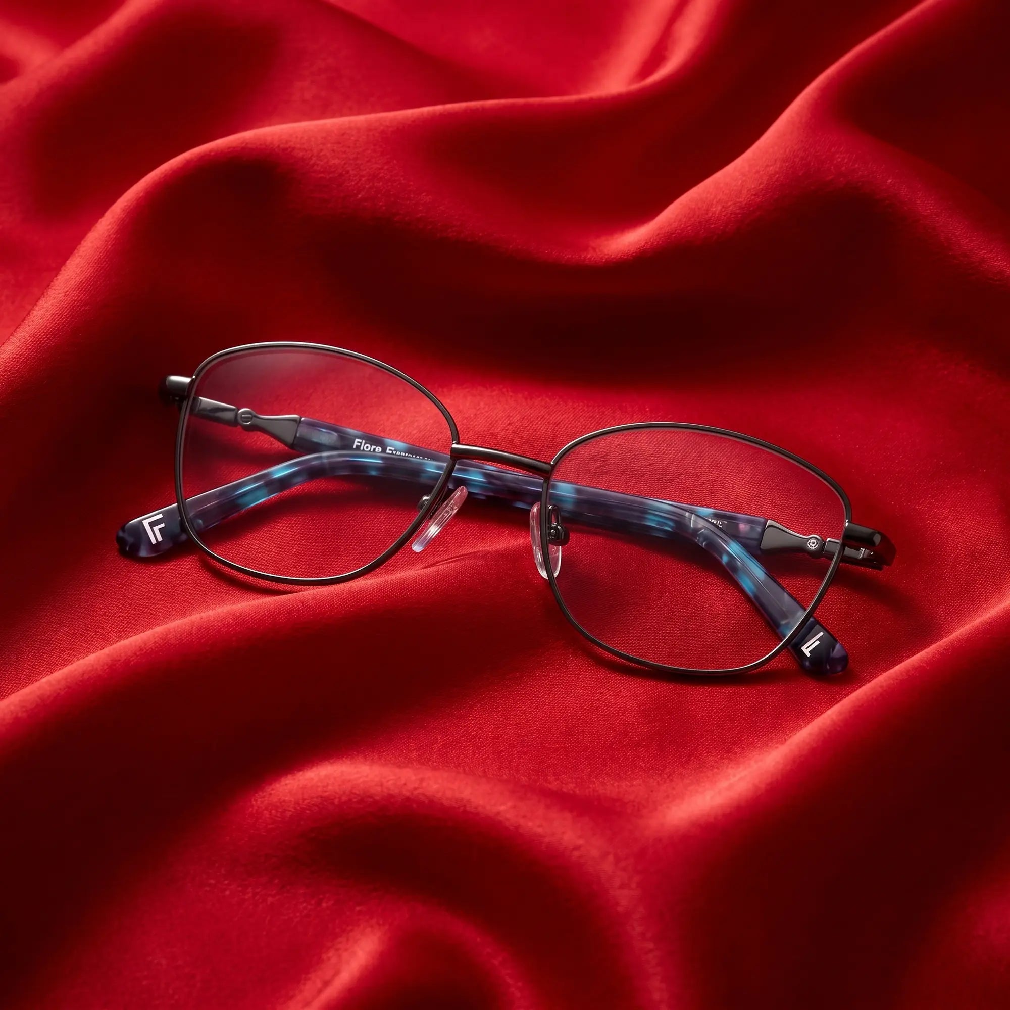 Fiore 2208 eyeglasses in gun blue – nested in flowing vivid red silk