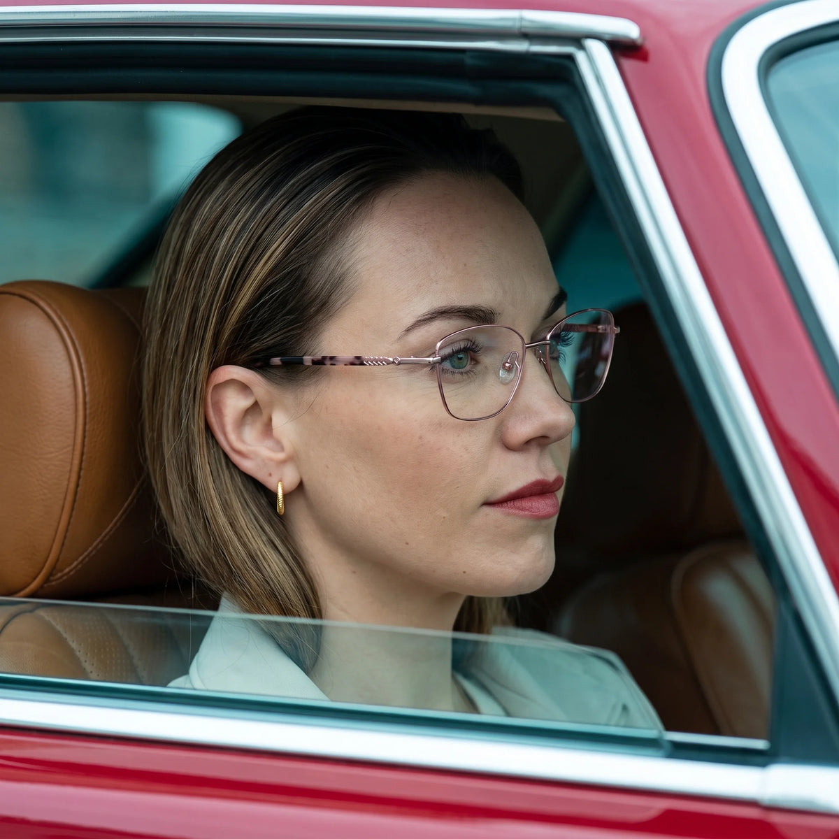 Fiore 2210 eyeglasses in pink, worn by a model – campaign portrait, gaze through a classic red car window