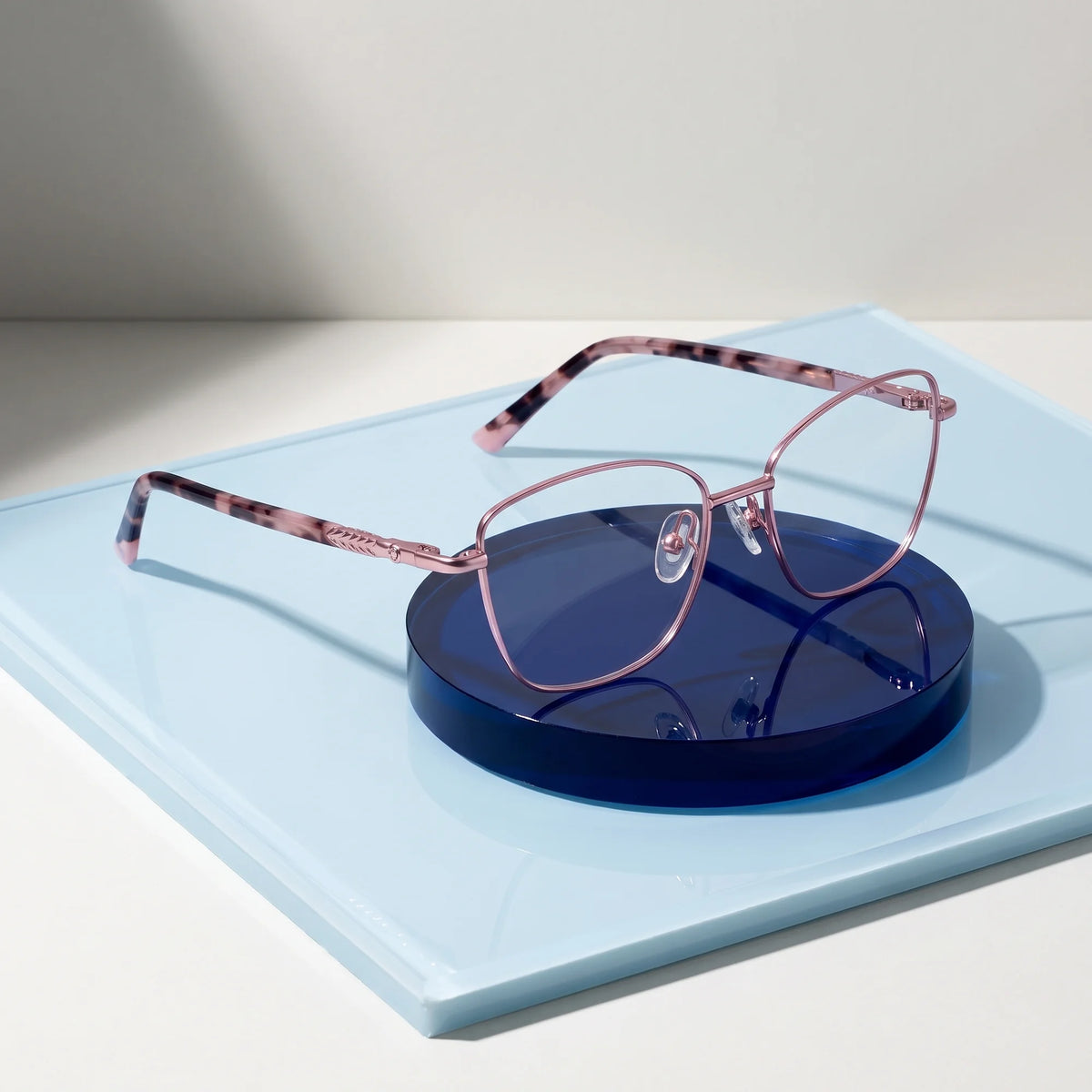 Fiore 2210 eyeglasses in pink – on a cobalt acrylic disc in soft daylight