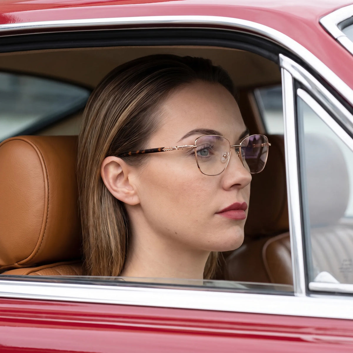 Fiore 2210 eyeglasses in gold pink, worn by a model – campaign portrait, gaze through a classic red car window