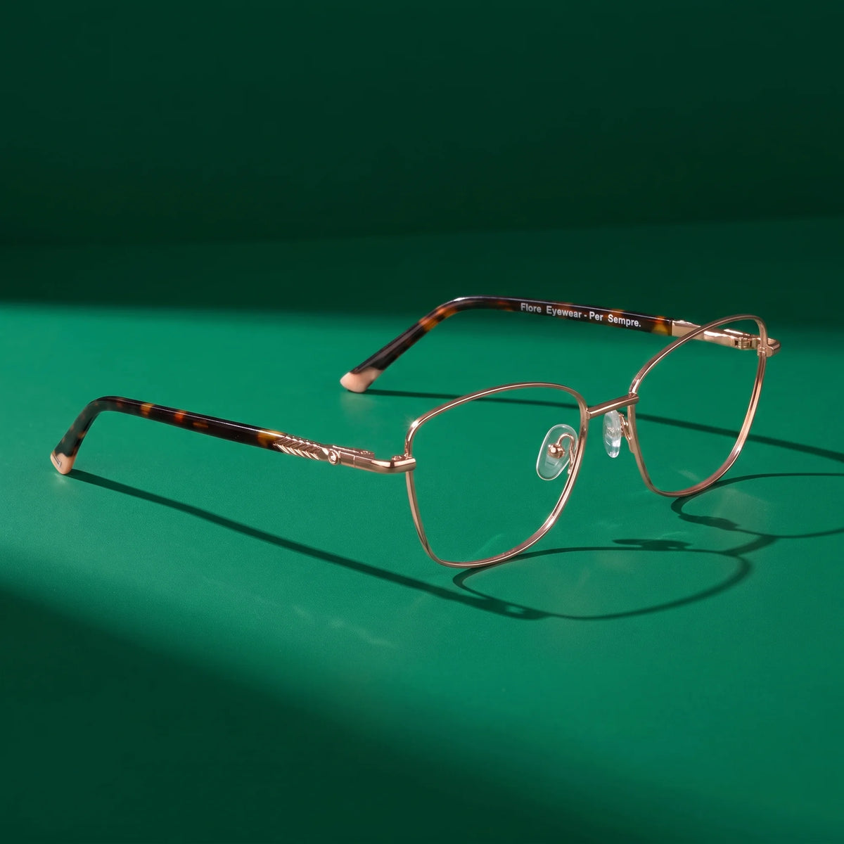Fiore 2210 eyeglasses in gold pink – editorial still life on a saturated emerald set
