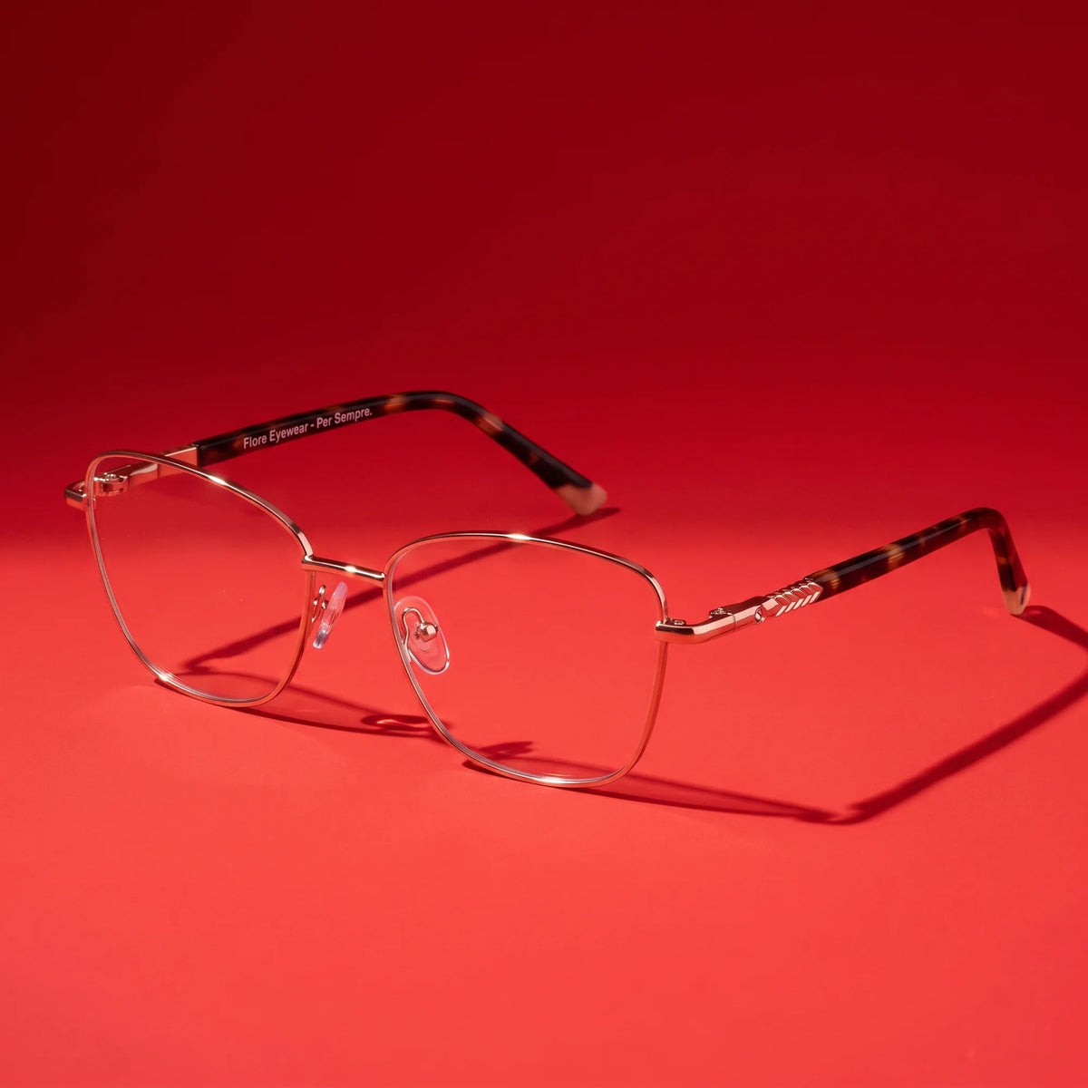 Fiore 2210 eyeglasses in gold pink – hero still life against a deep vivid red backdrop